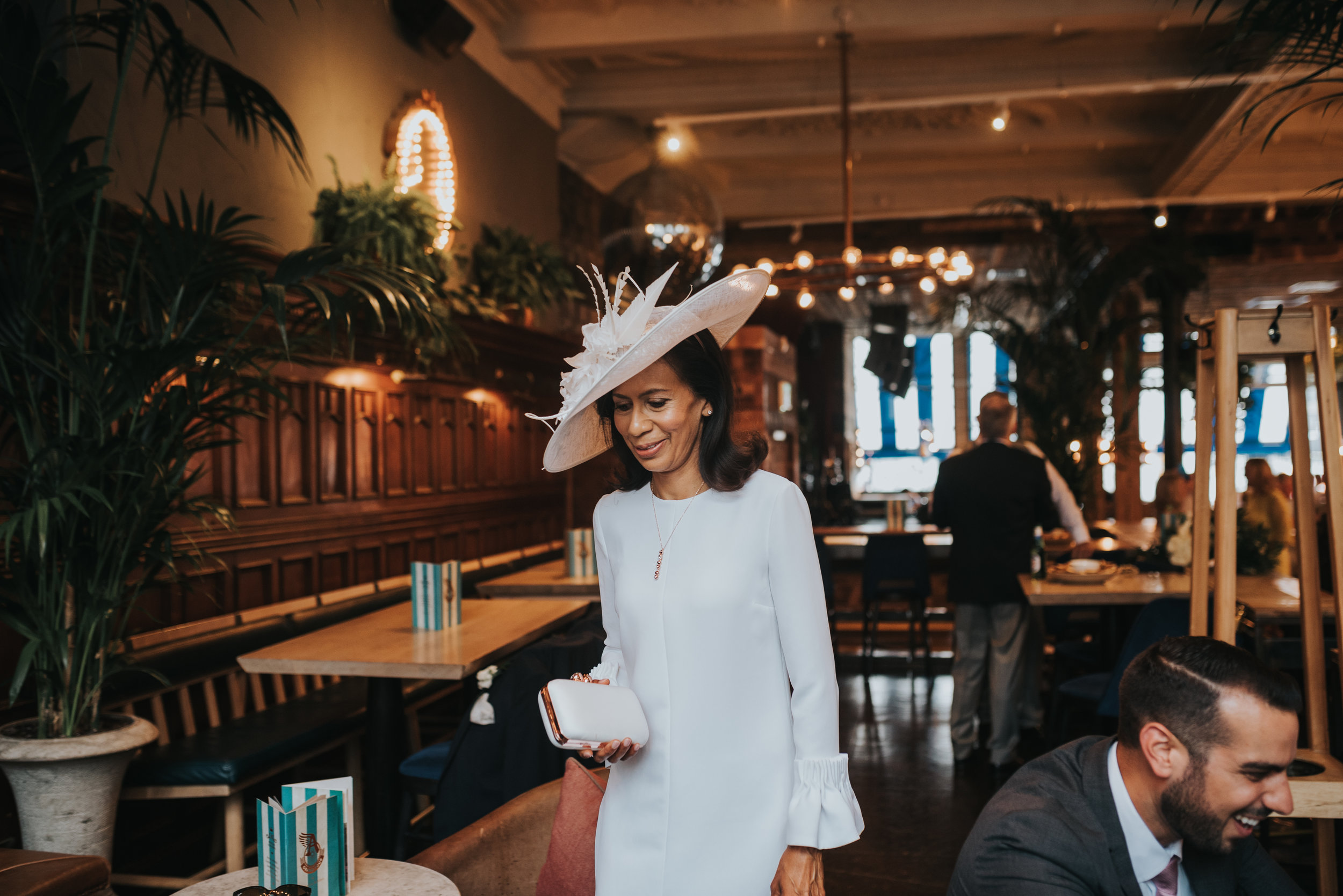 Mother of the bride wearing a creme suit and hat. 