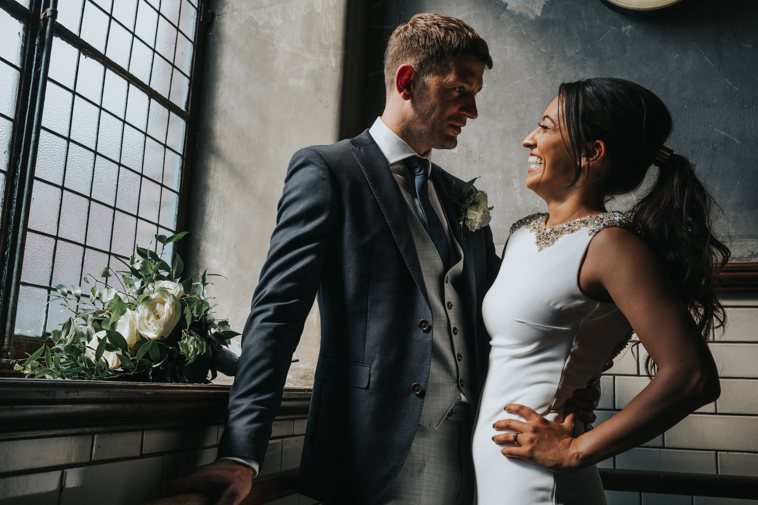 Bride and groom stand smiling together. 