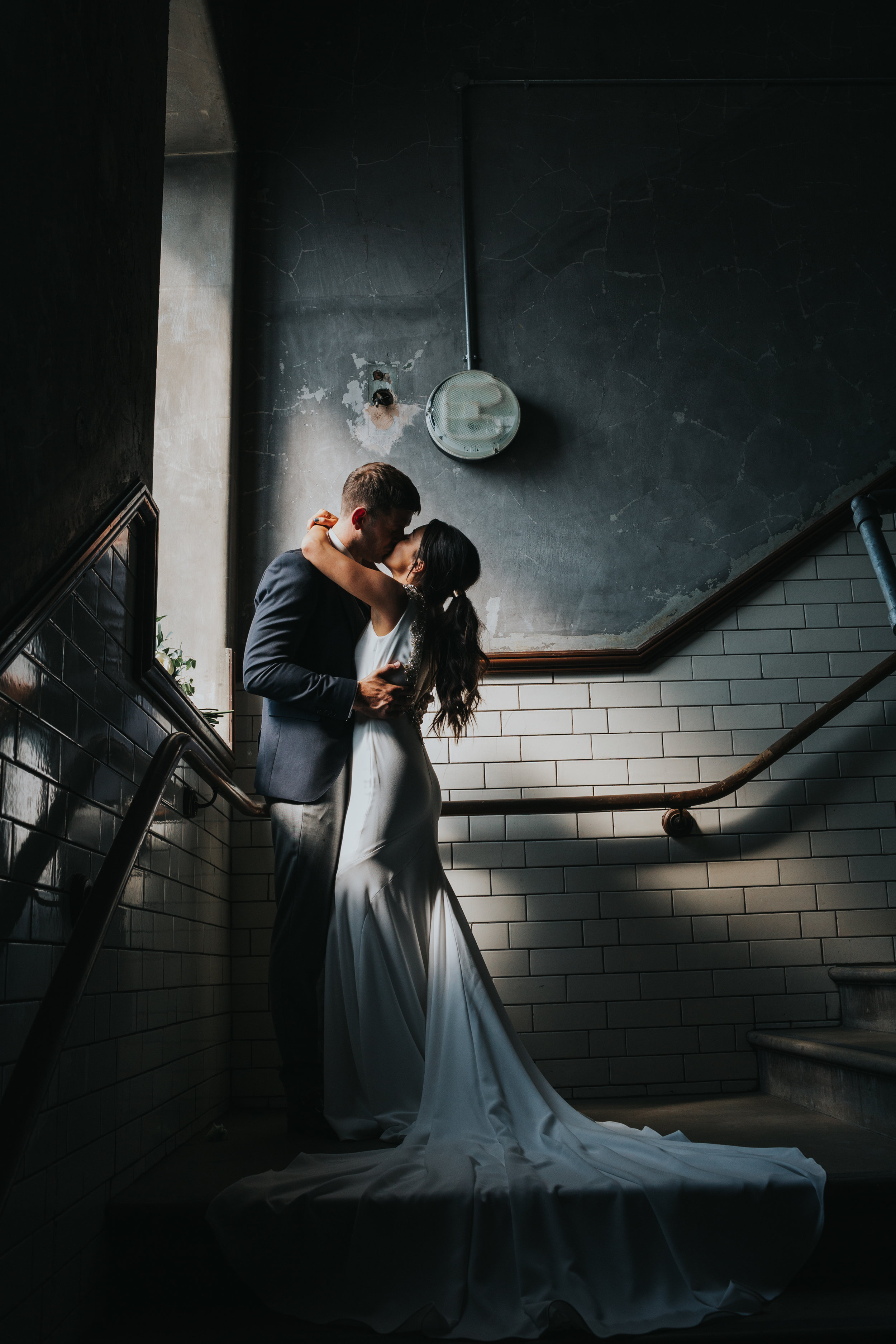 Bride and groom kiss in window light, Albert Hall Manchester. 