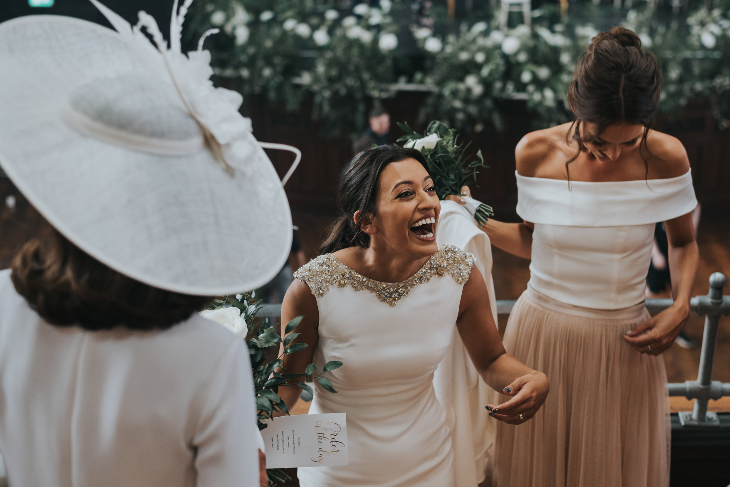 Bride laughing with mother of the bride and her bridesmaid.