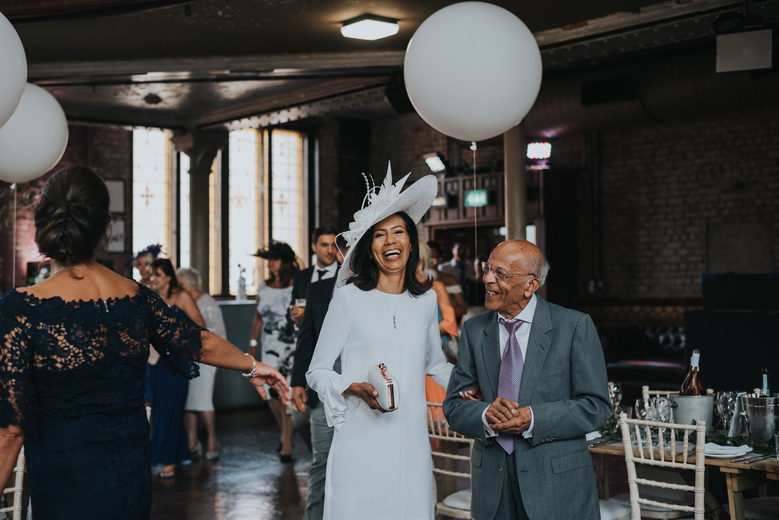 Mother of the bride and her father hold hands. 