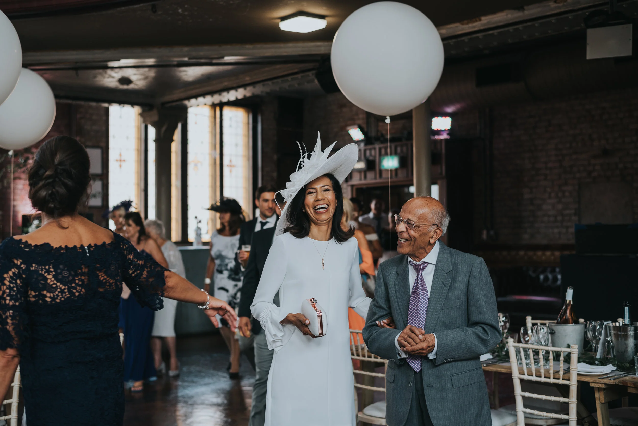 Mother of the bride and her father hold hands.
