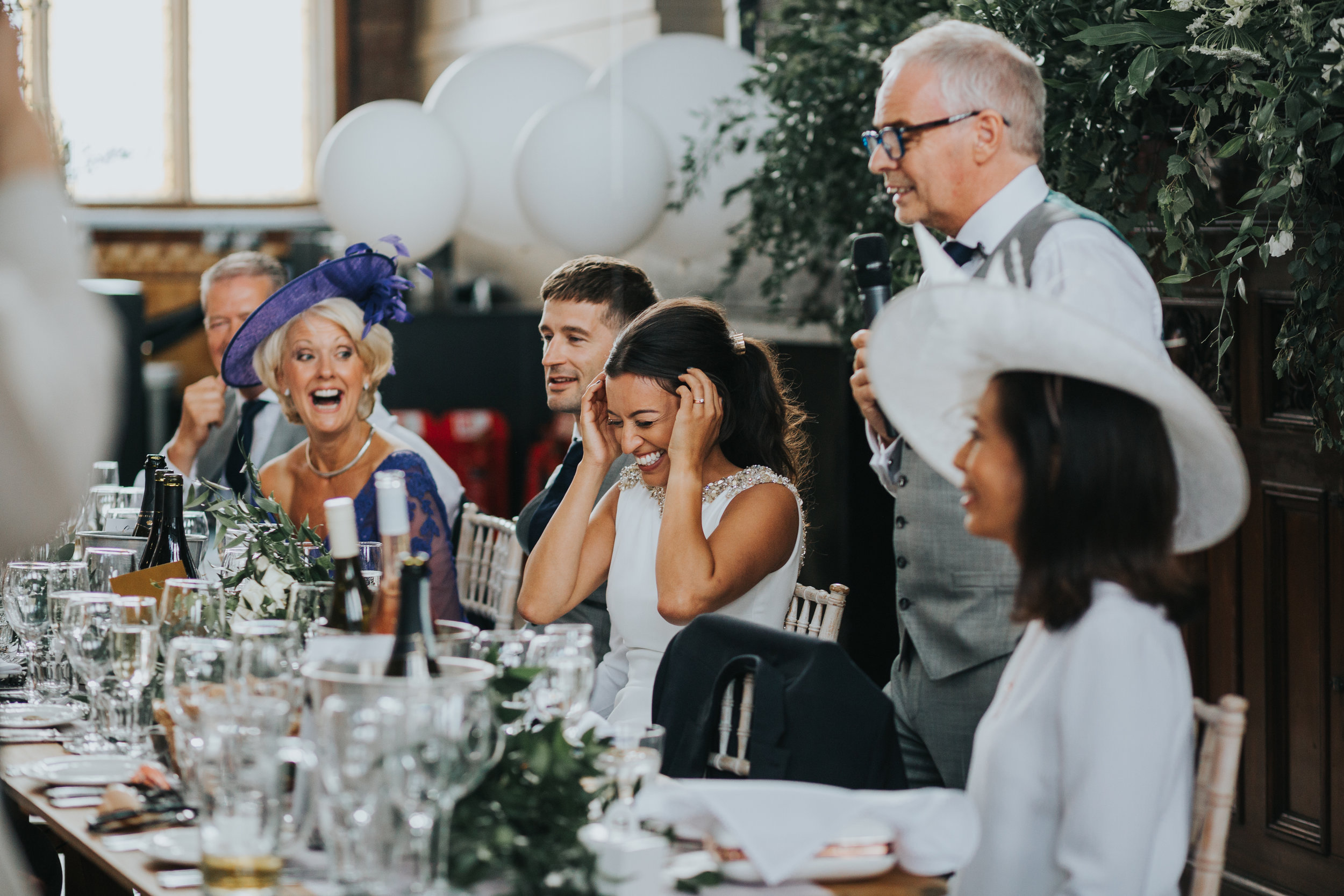 Bride laughs while listening to fathers speech. 