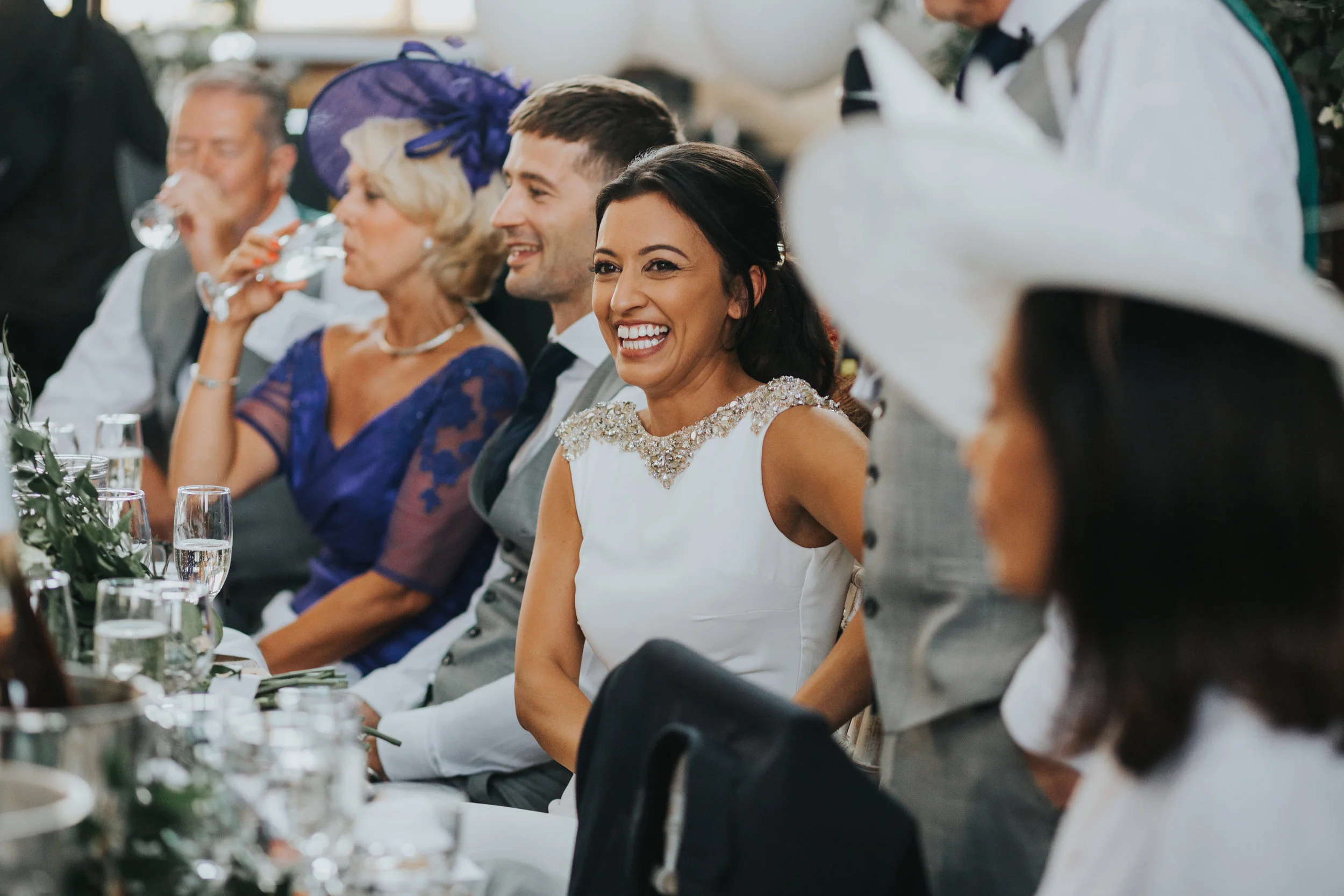 Bride smiles listening to fathers speech.