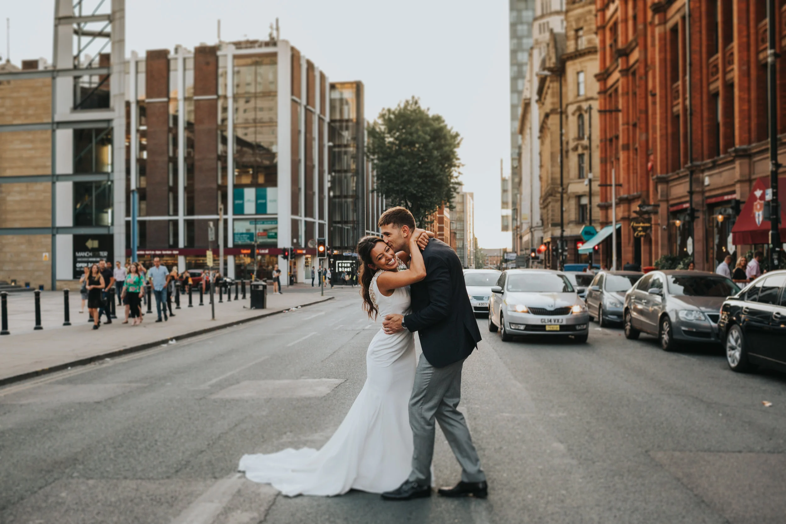 Bride and groom stand laughing in the middle of the road.