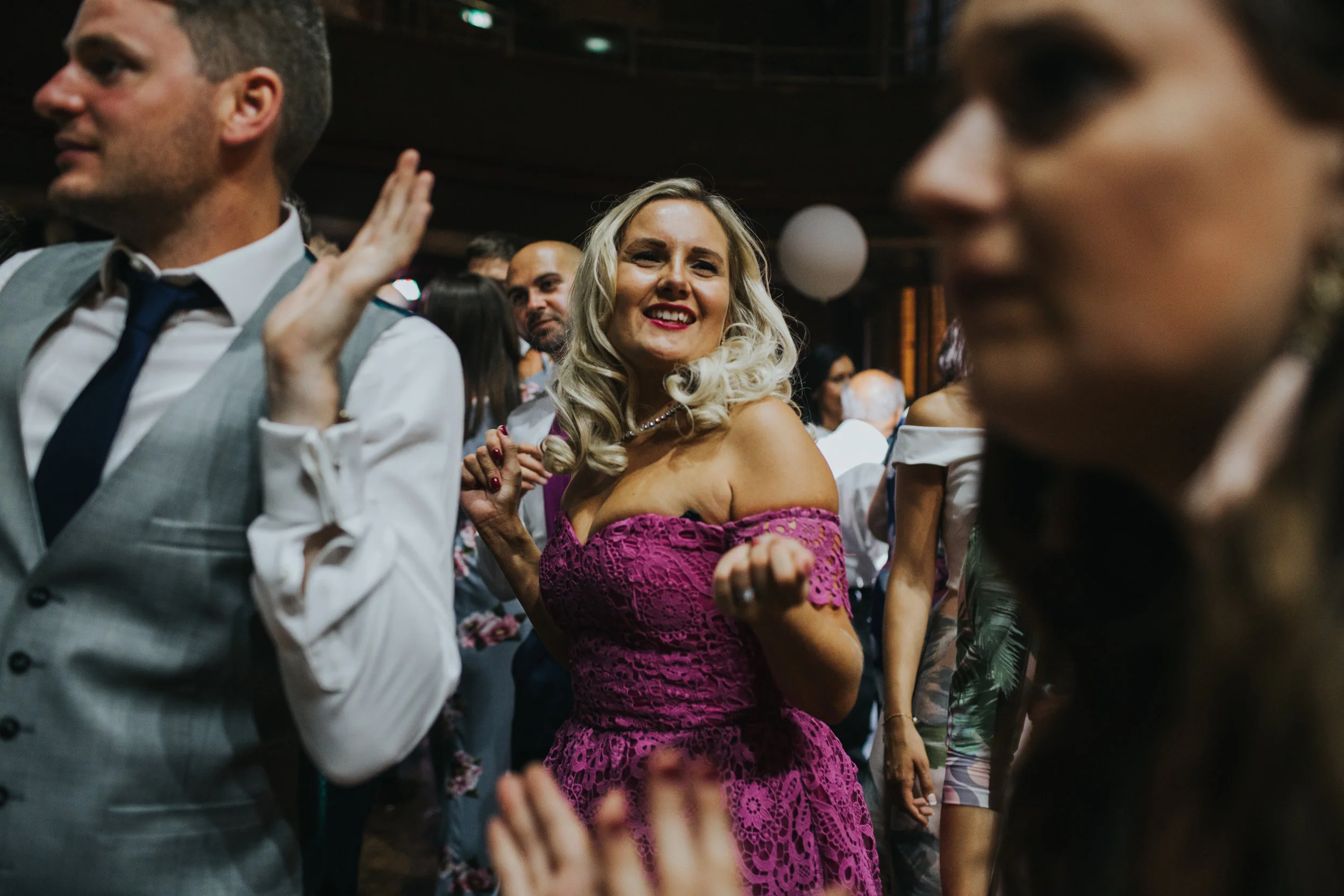 Blonde wedding guest smiles dancing in the crown.