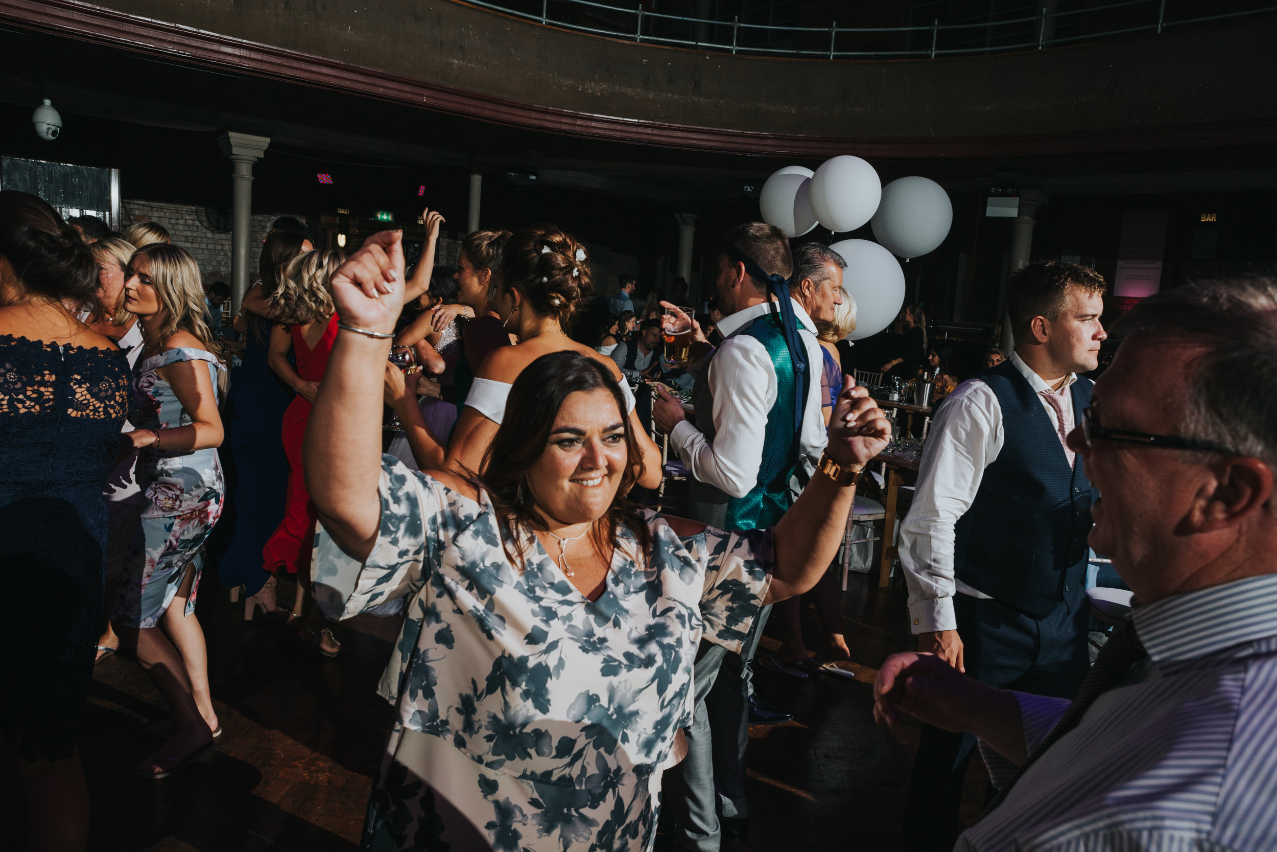 Female wedding guest dances raising her hand s in the air. 