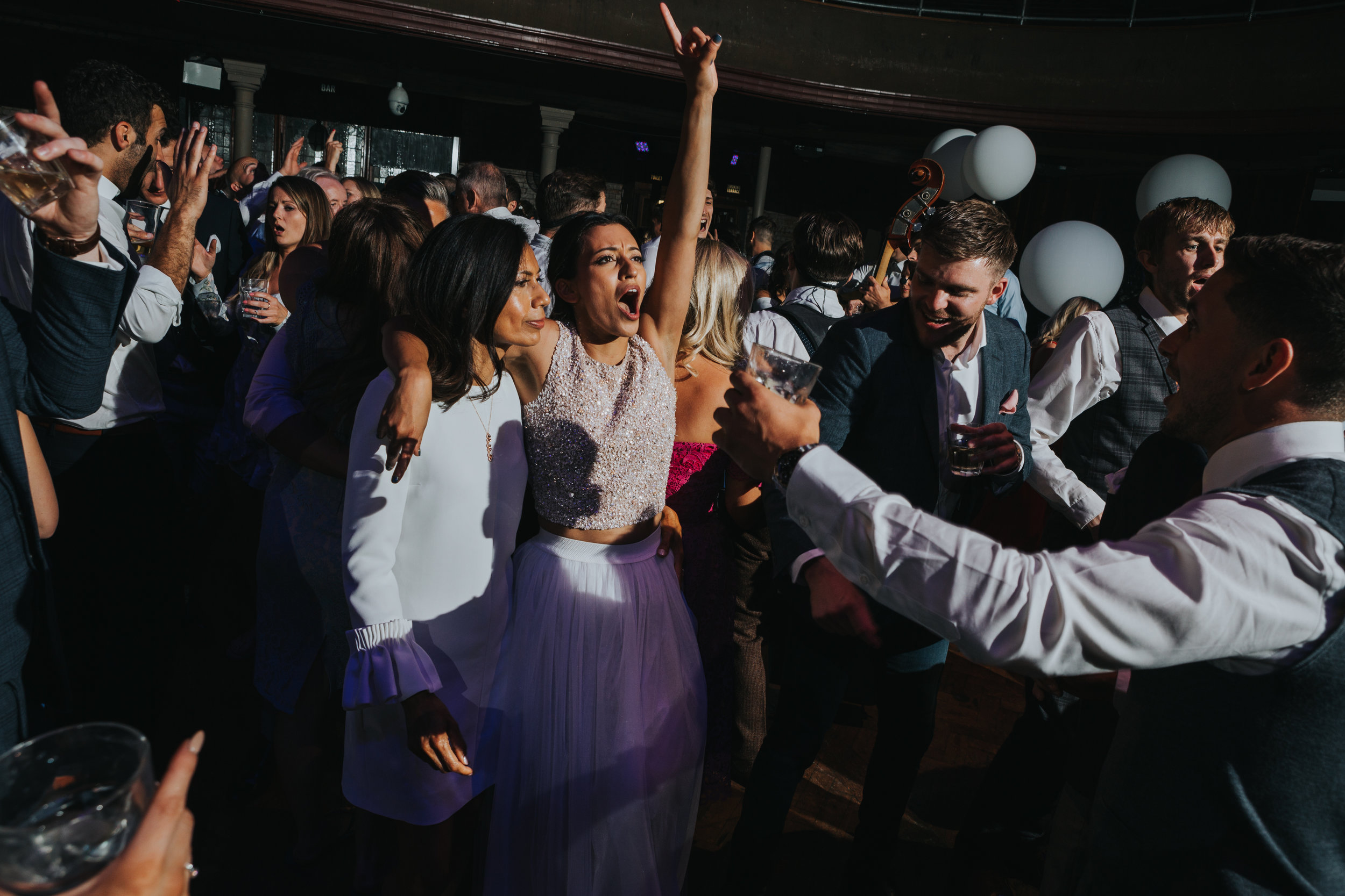 Bride raises her hand in the air singing to the music. 