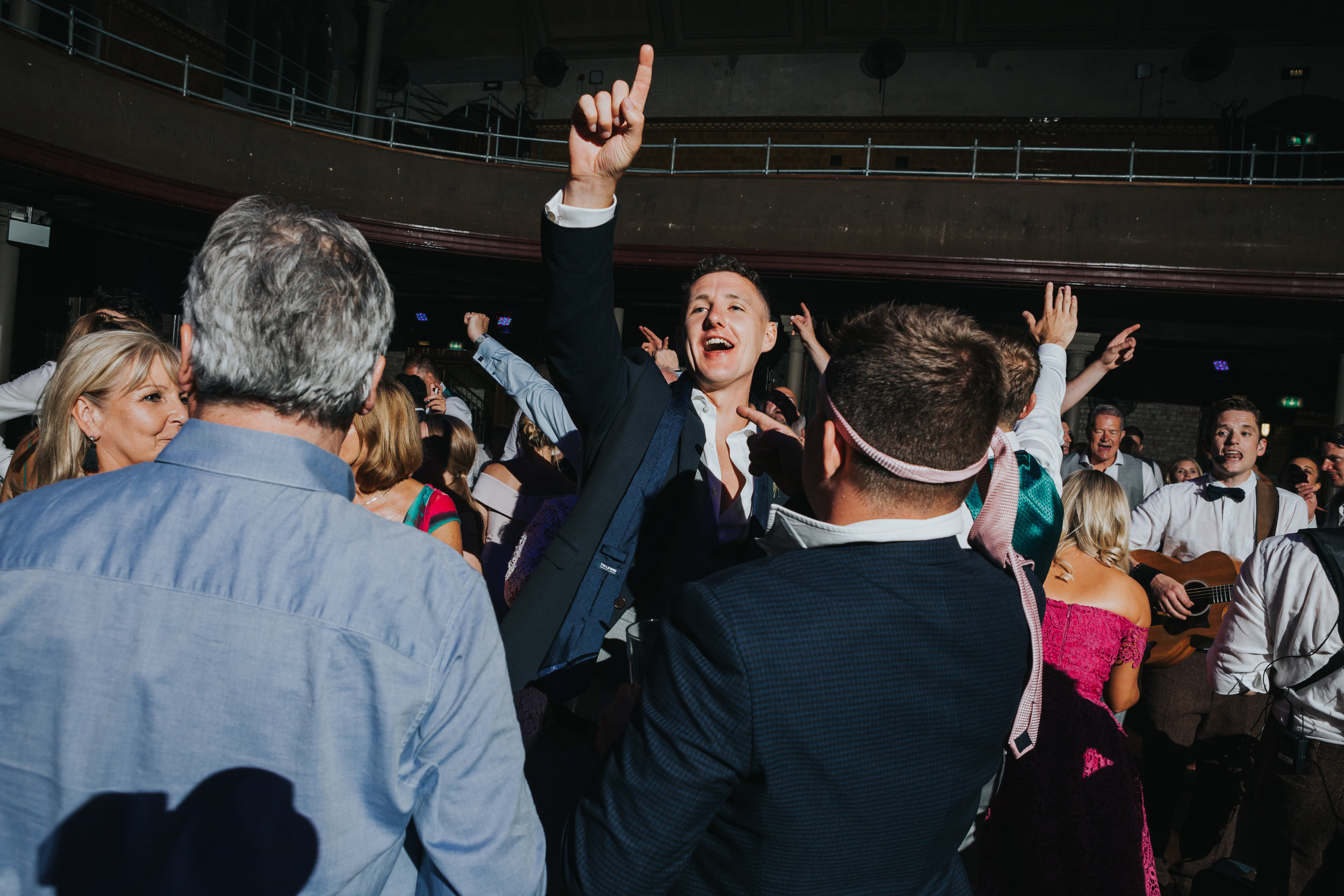Male weddings guests dance with their ties tied around their heads, Rambo style. 