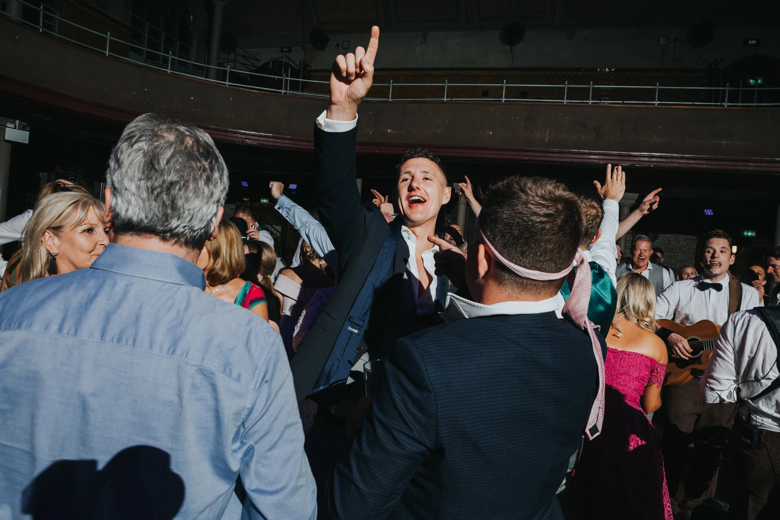 Male weddings guests dance with their ties tied around their heads, Rambo style.