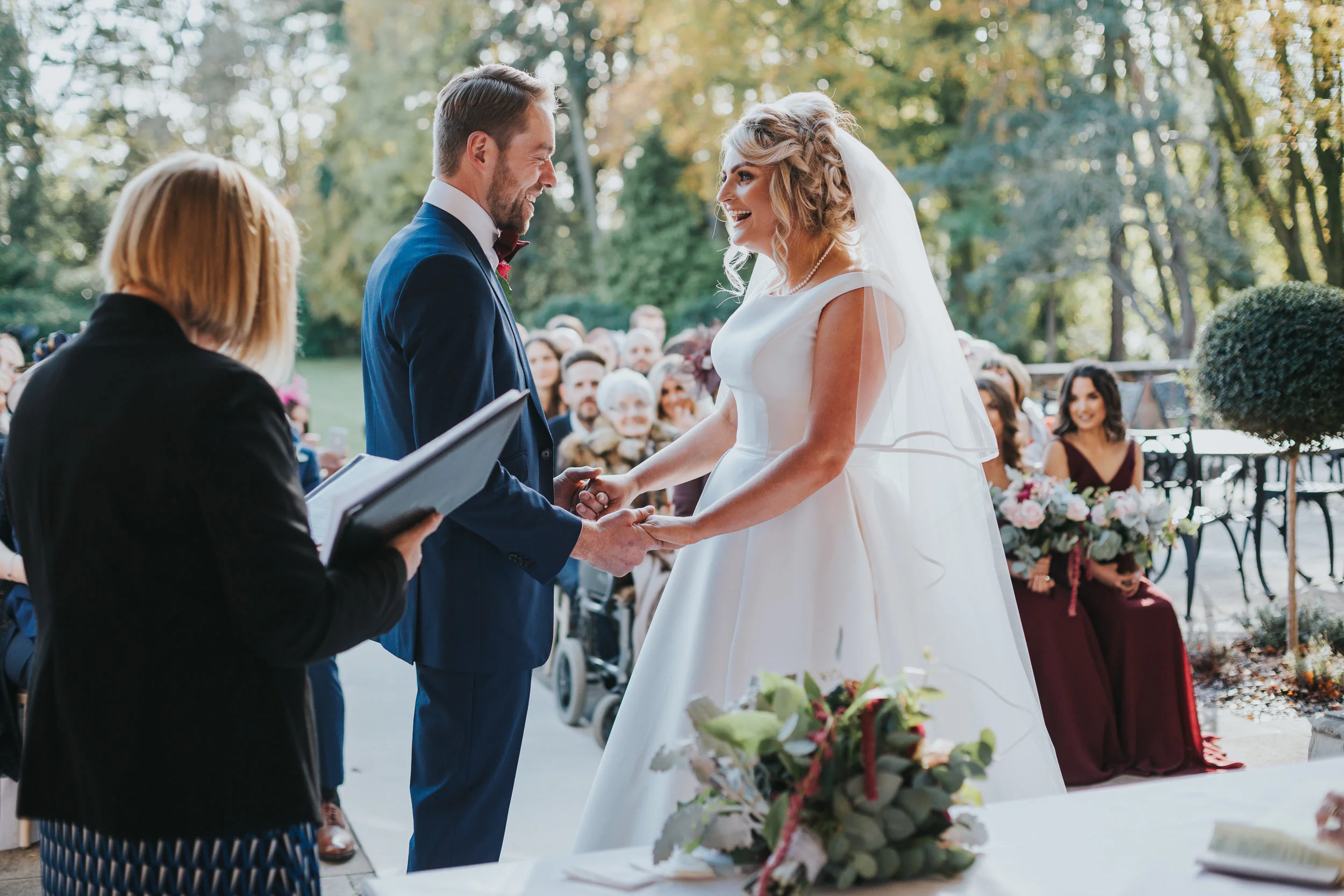 Bride and Groom stand facing each other, holding hands and looking to each others eyes playfully.