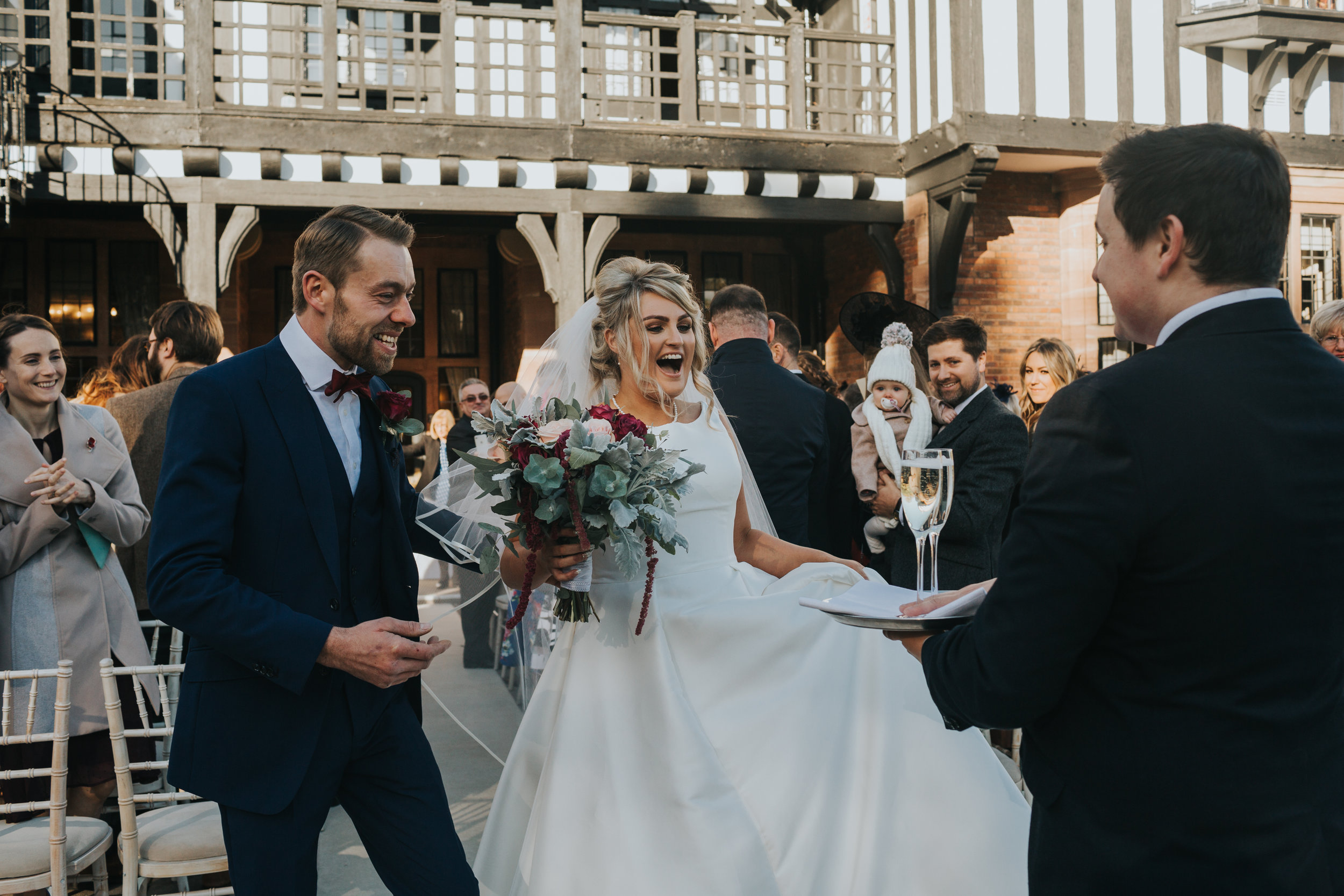 Bride and Groom are greeted with 2 glasses of champagne at the end of the aisle by staff member. 