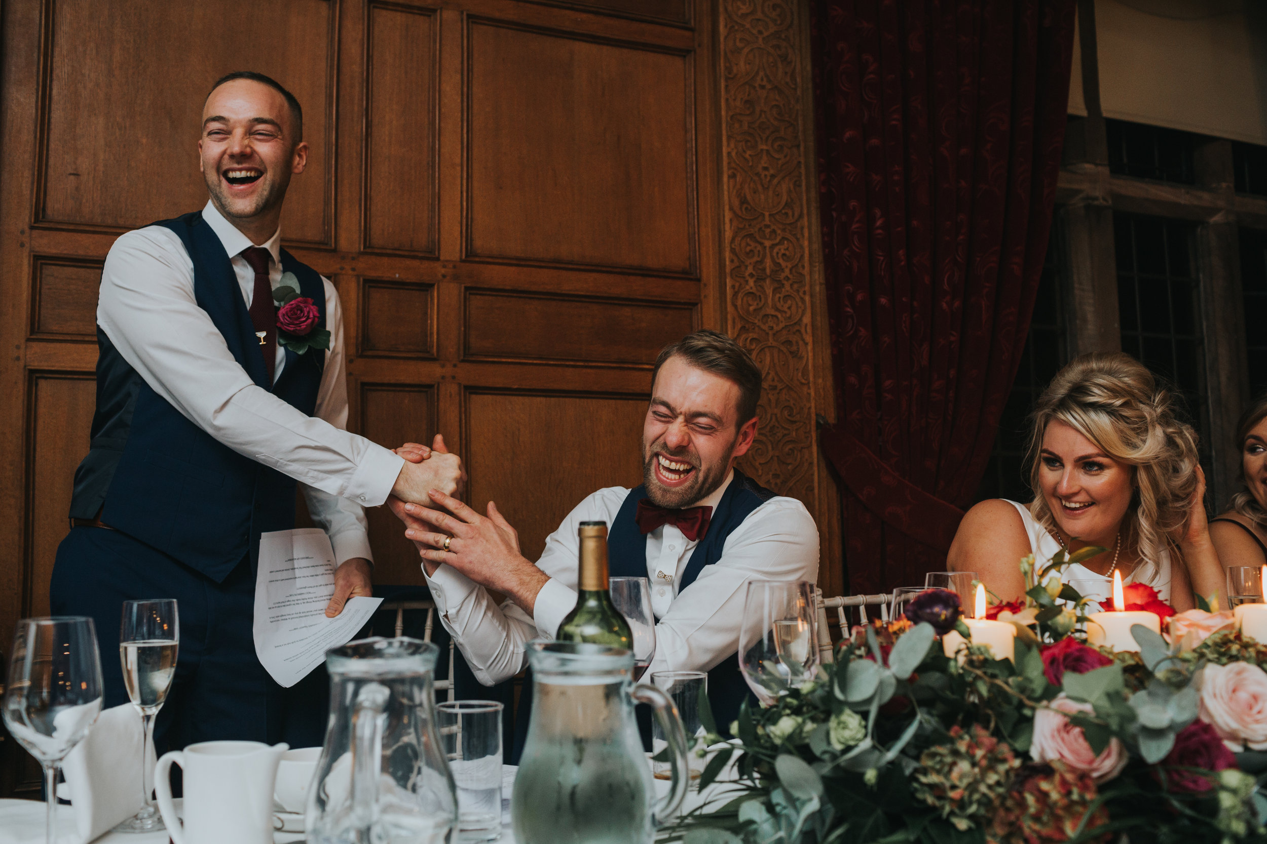 The Groom and Best Man smile laughing together.