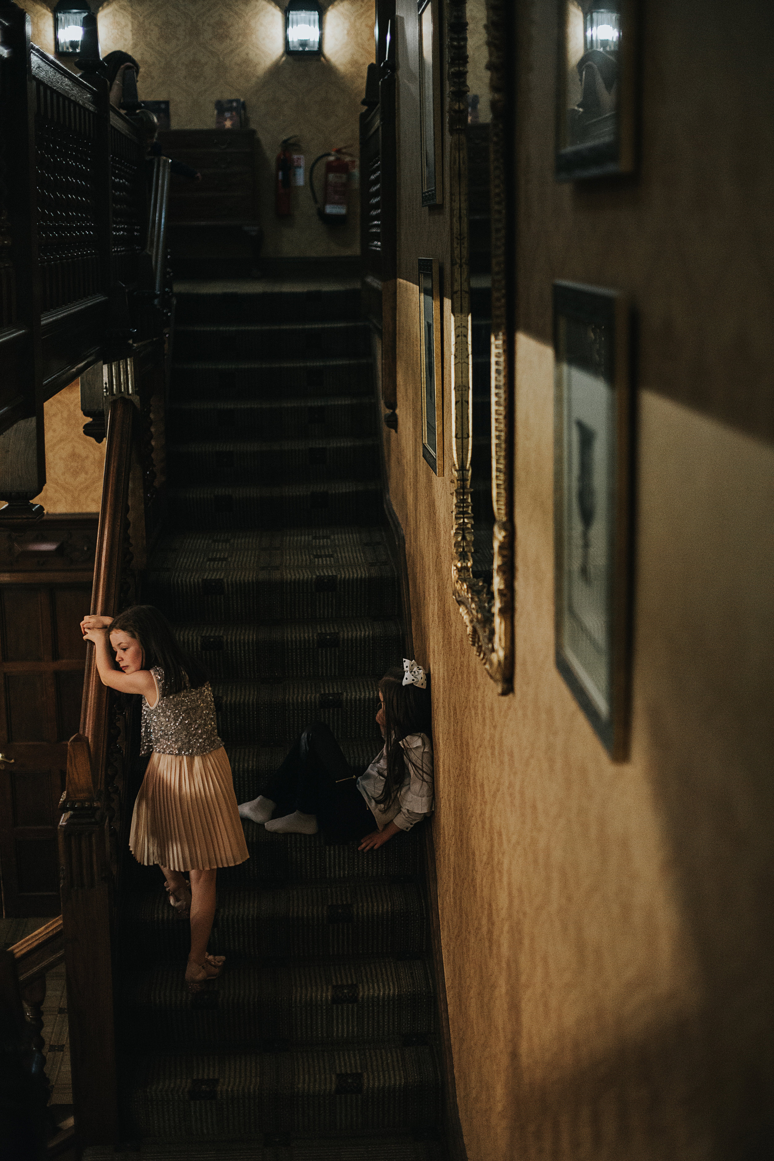 Little girls watch wedding guests from the stairs.