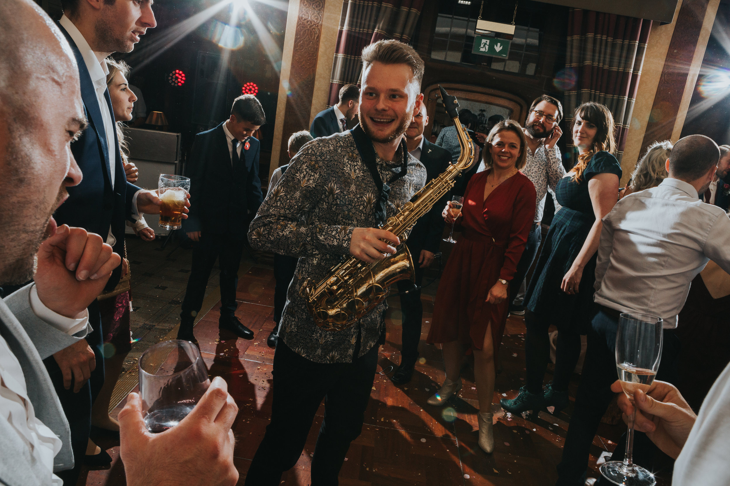 Saxophone player smiles at guests giving it their all on the dance floor. 