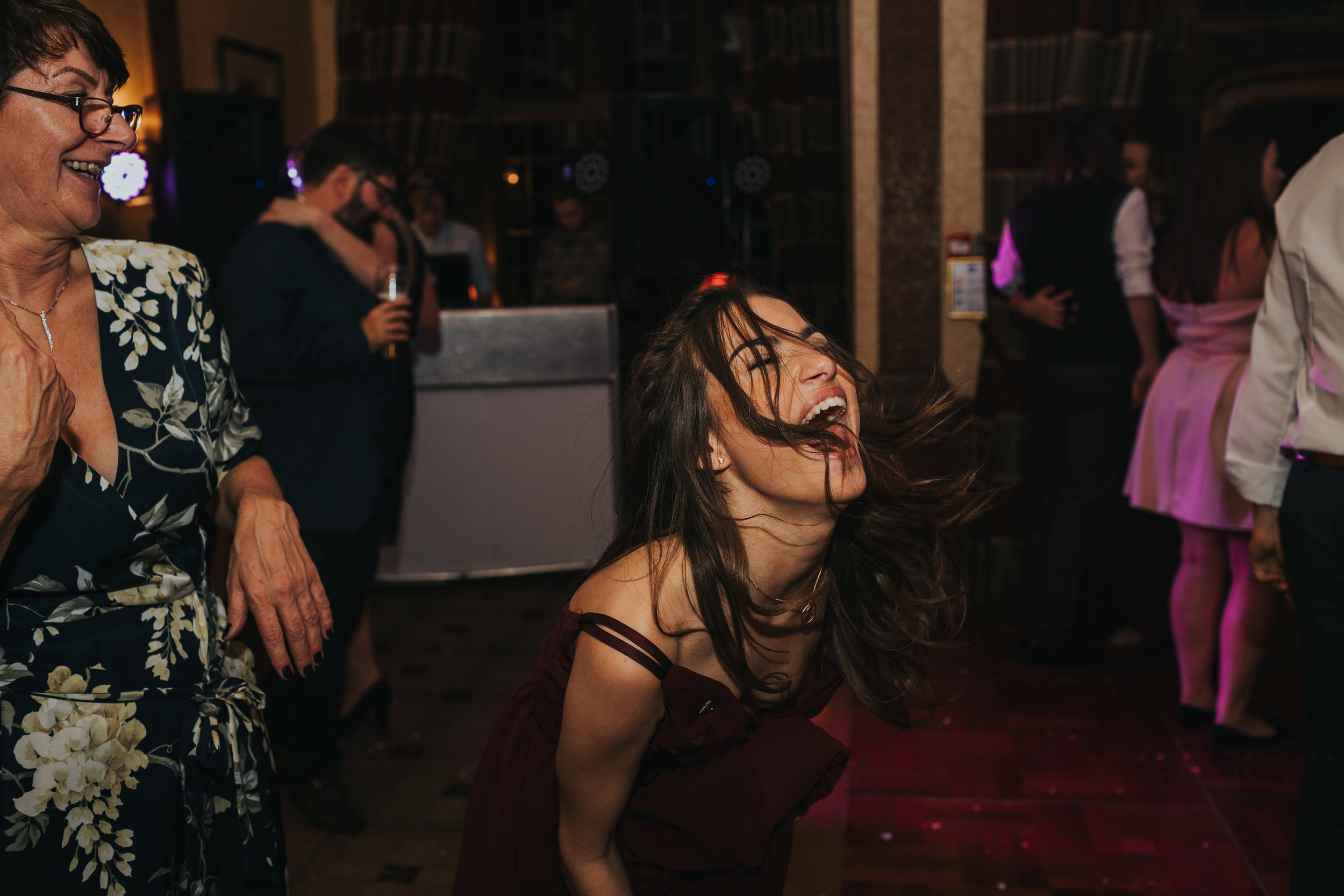 Bridesmaid shouts out and throws her head back as she dances. 