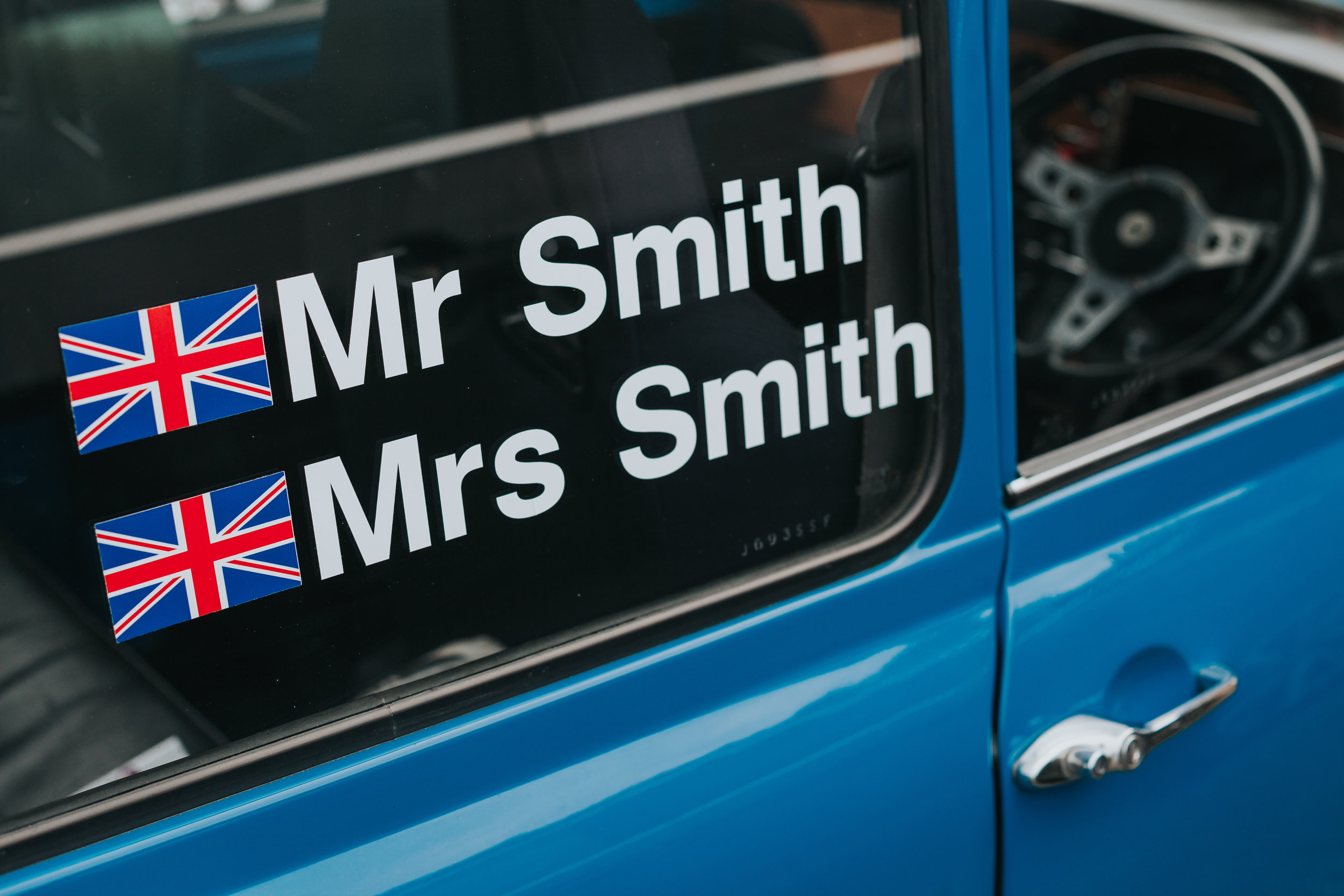 Window of a blue mini, with Mr and Mrs Smith written on it. 