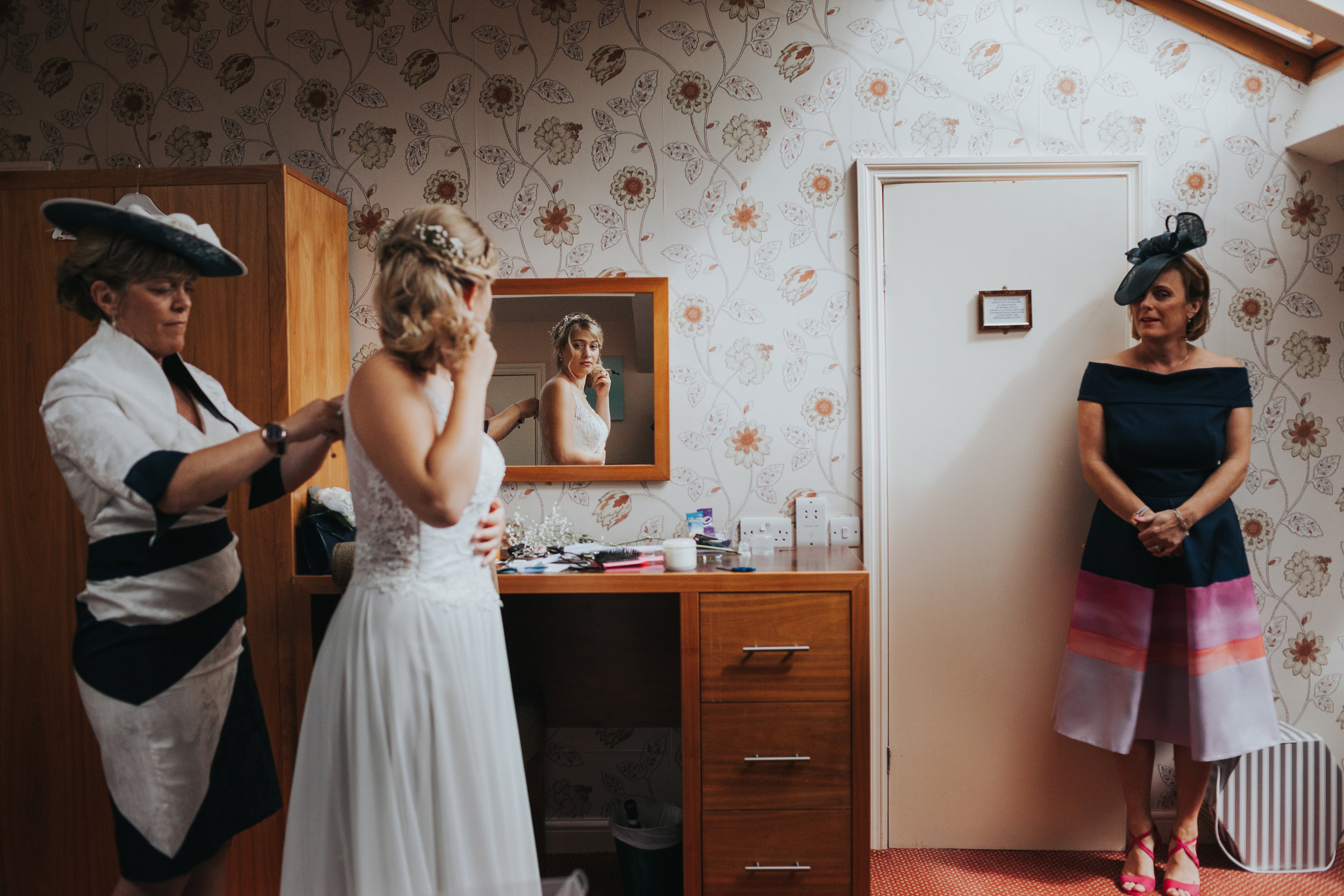 The bride to be is helped into her dress by her mother at Mytton Folds.