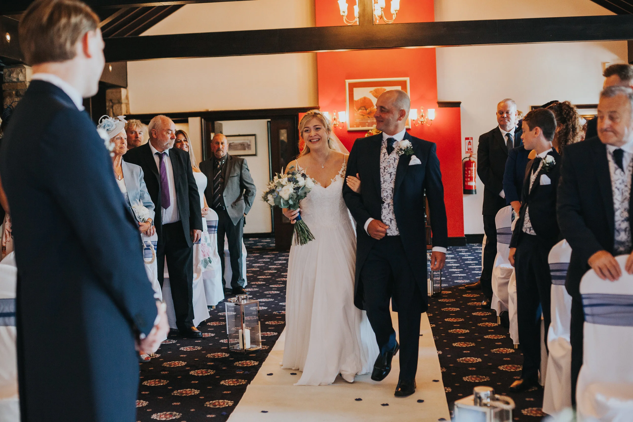 Bride is walked down the aisle by her father. 