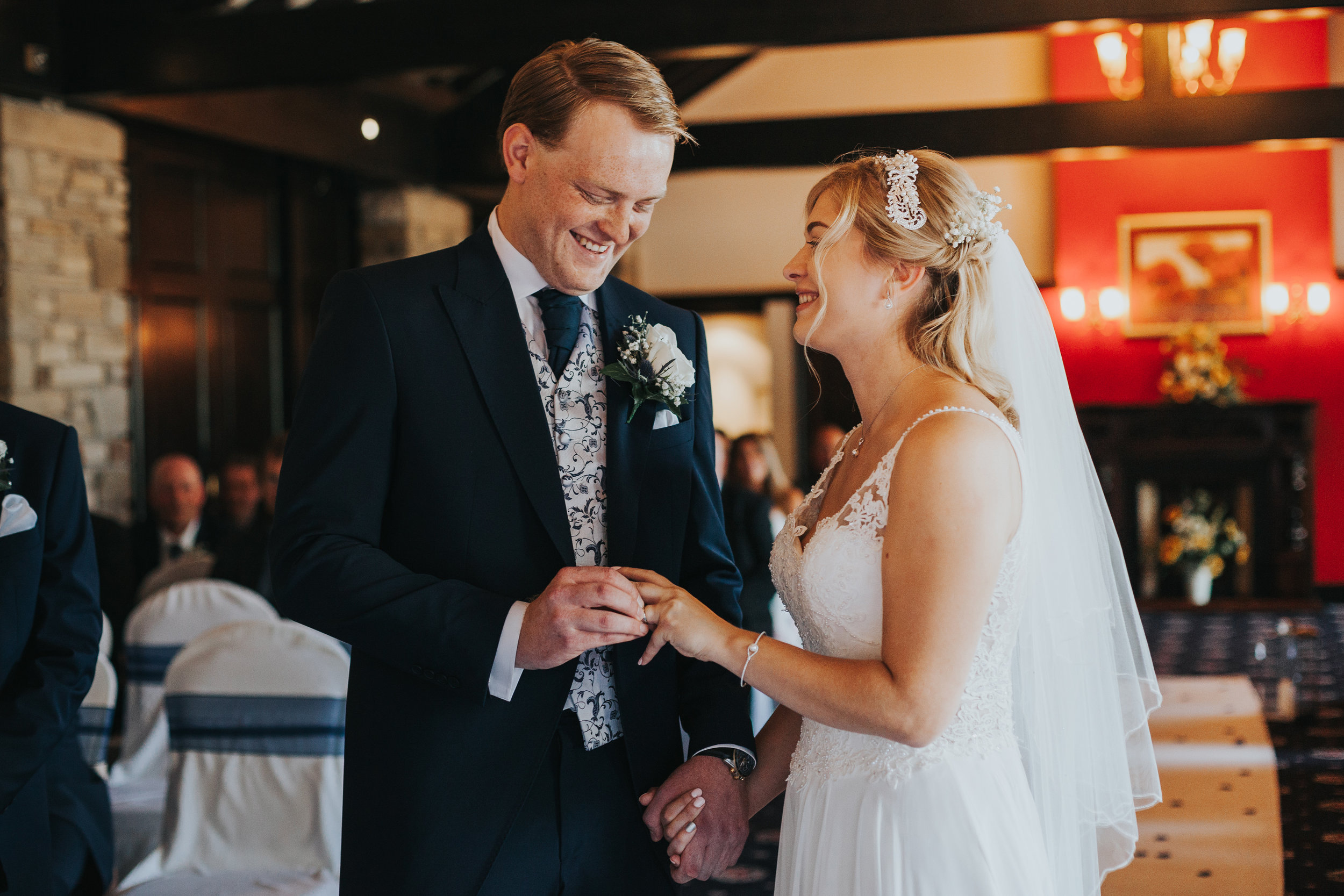 Bride and groom laugh while putting on their rings.