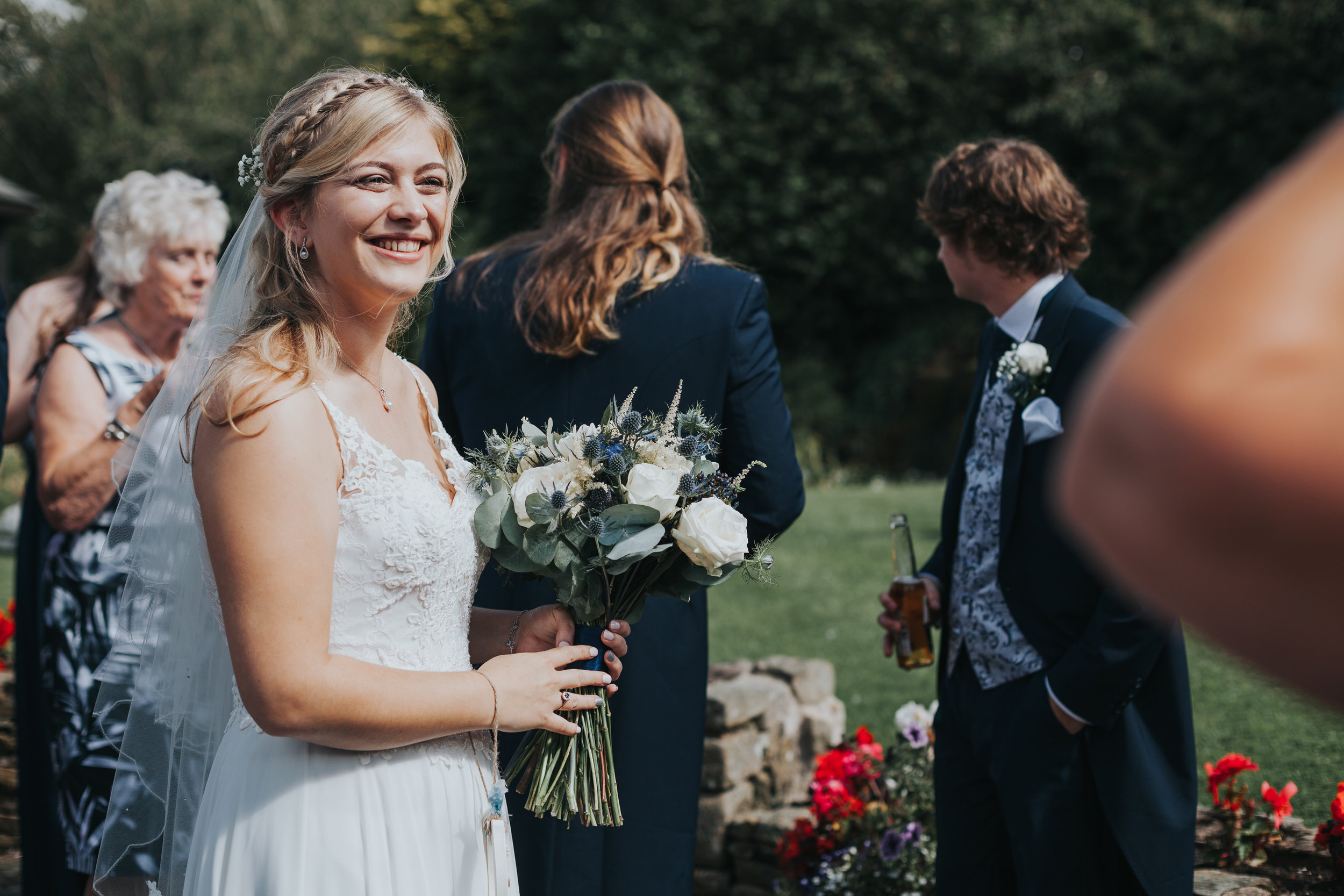 Outside bride smiles at wedding guests.