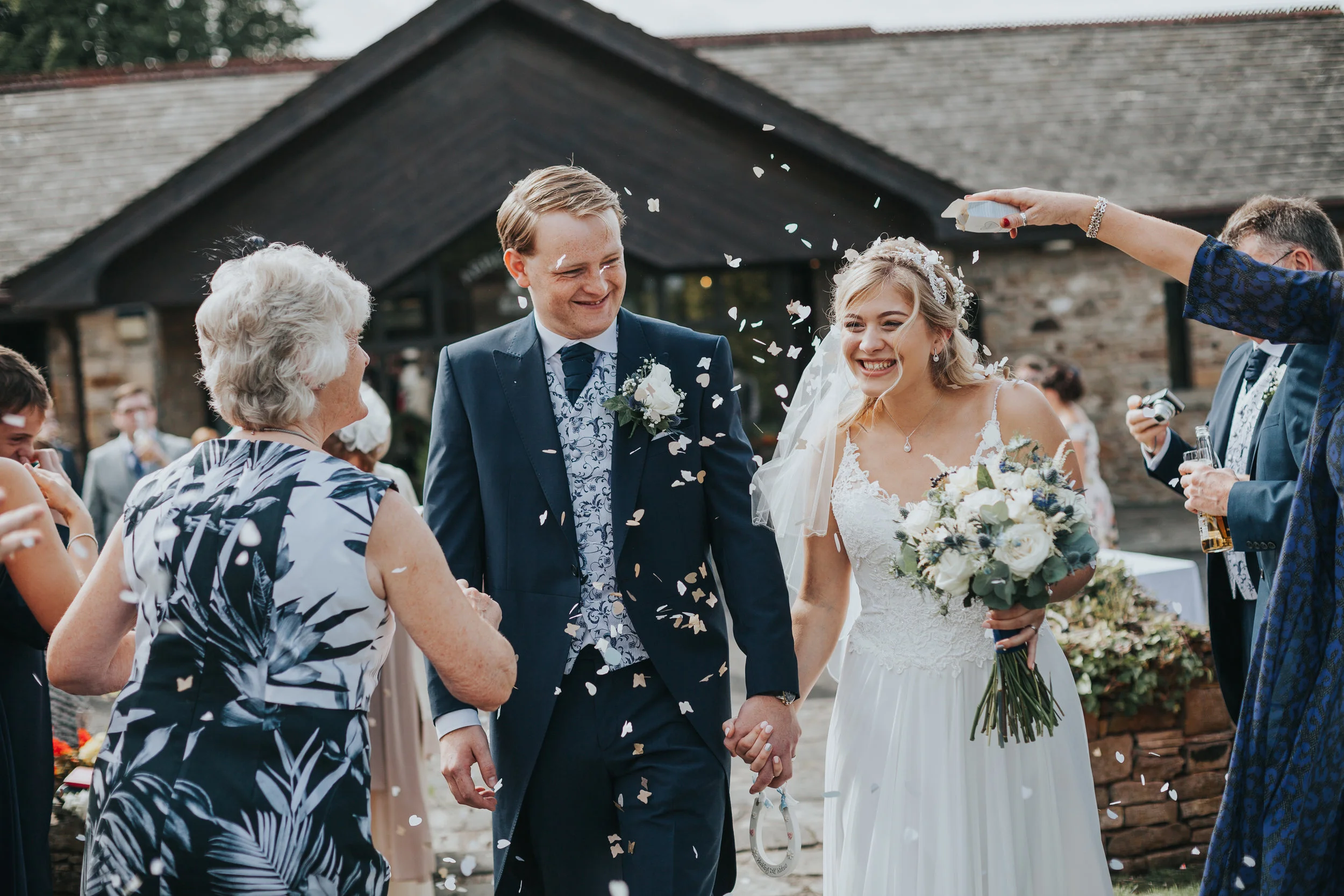 Bride and groom have confetti thrown at them. 