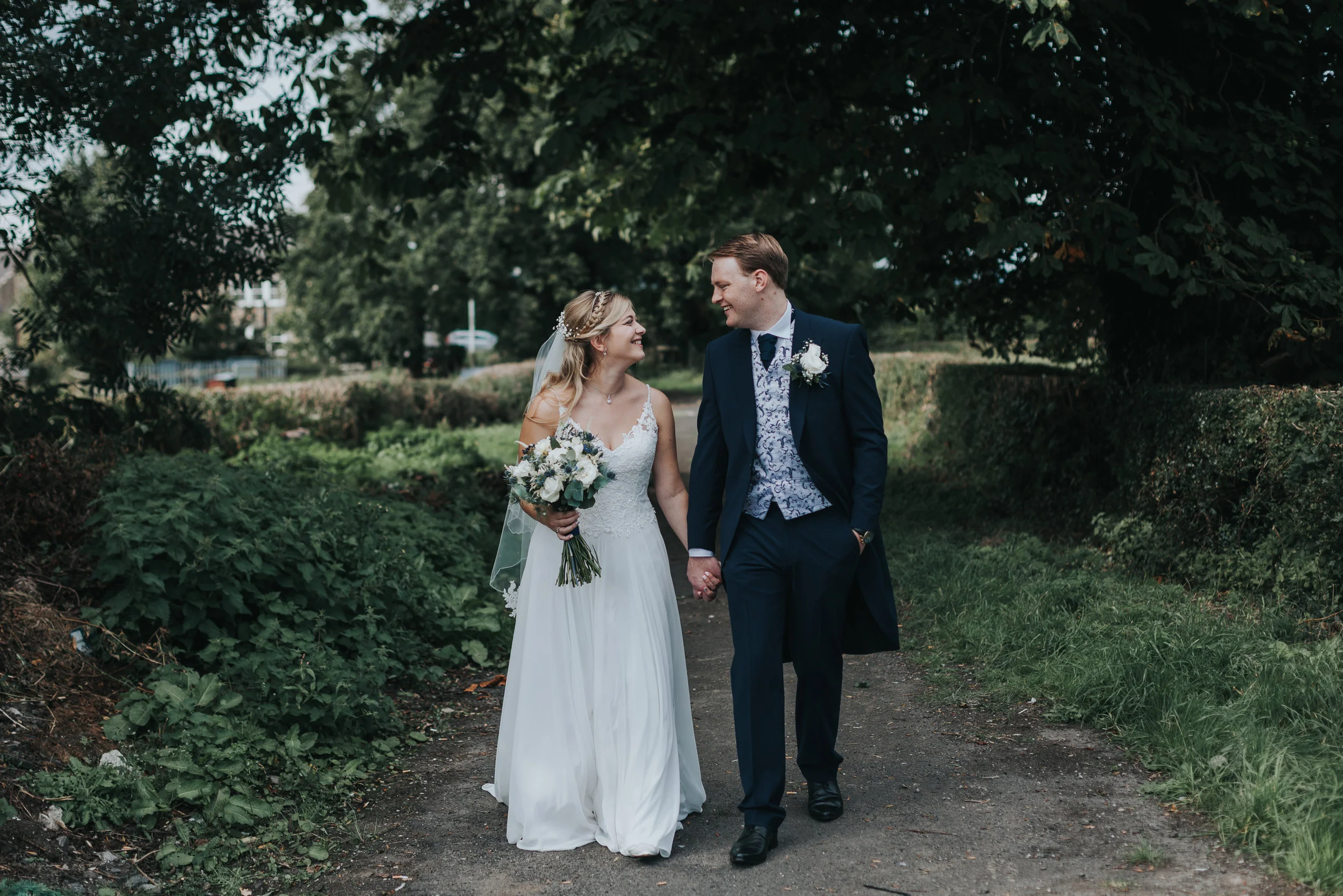 Bride and Groom walk down a country road chatting. 