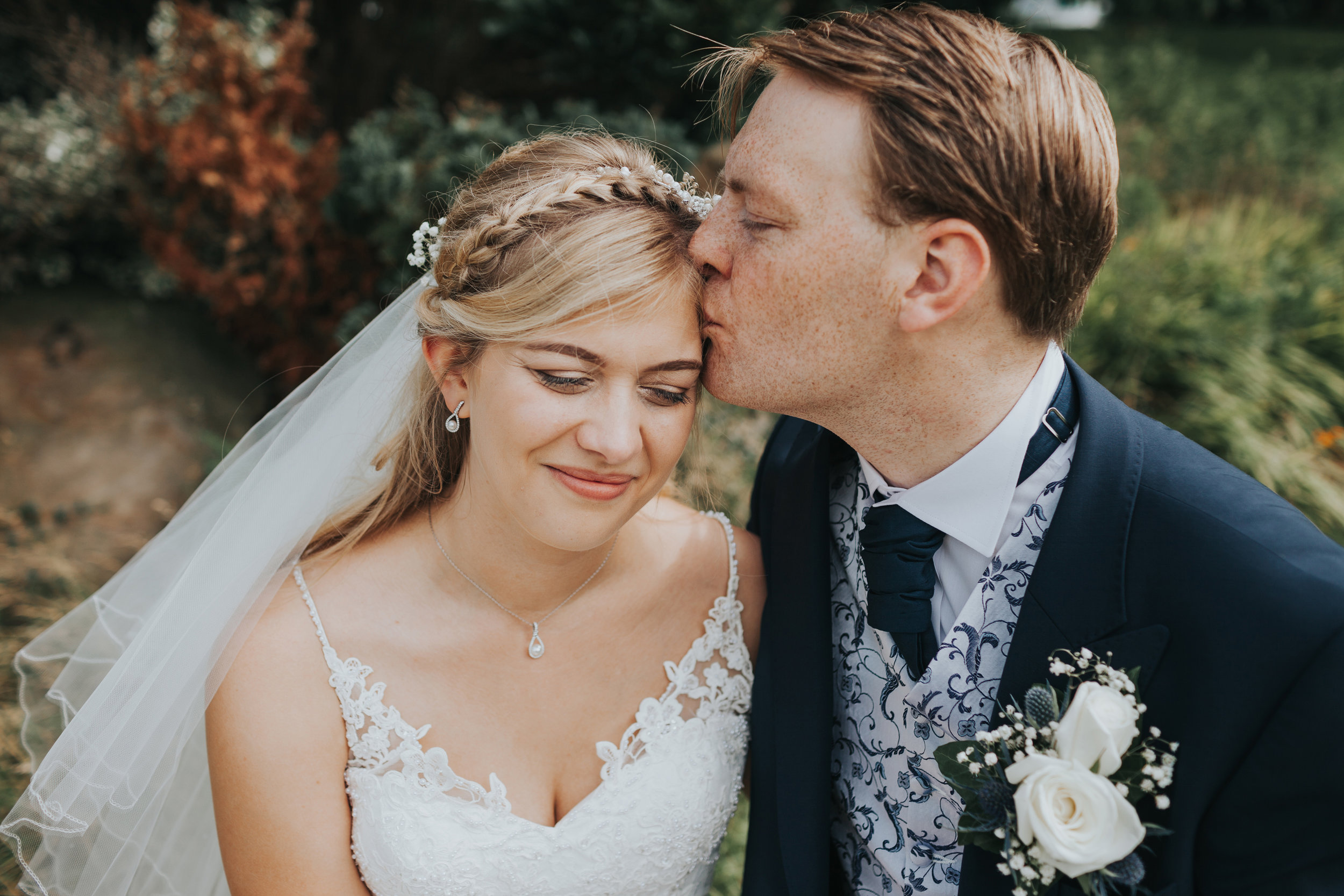 Groom kisses bride on the head. 