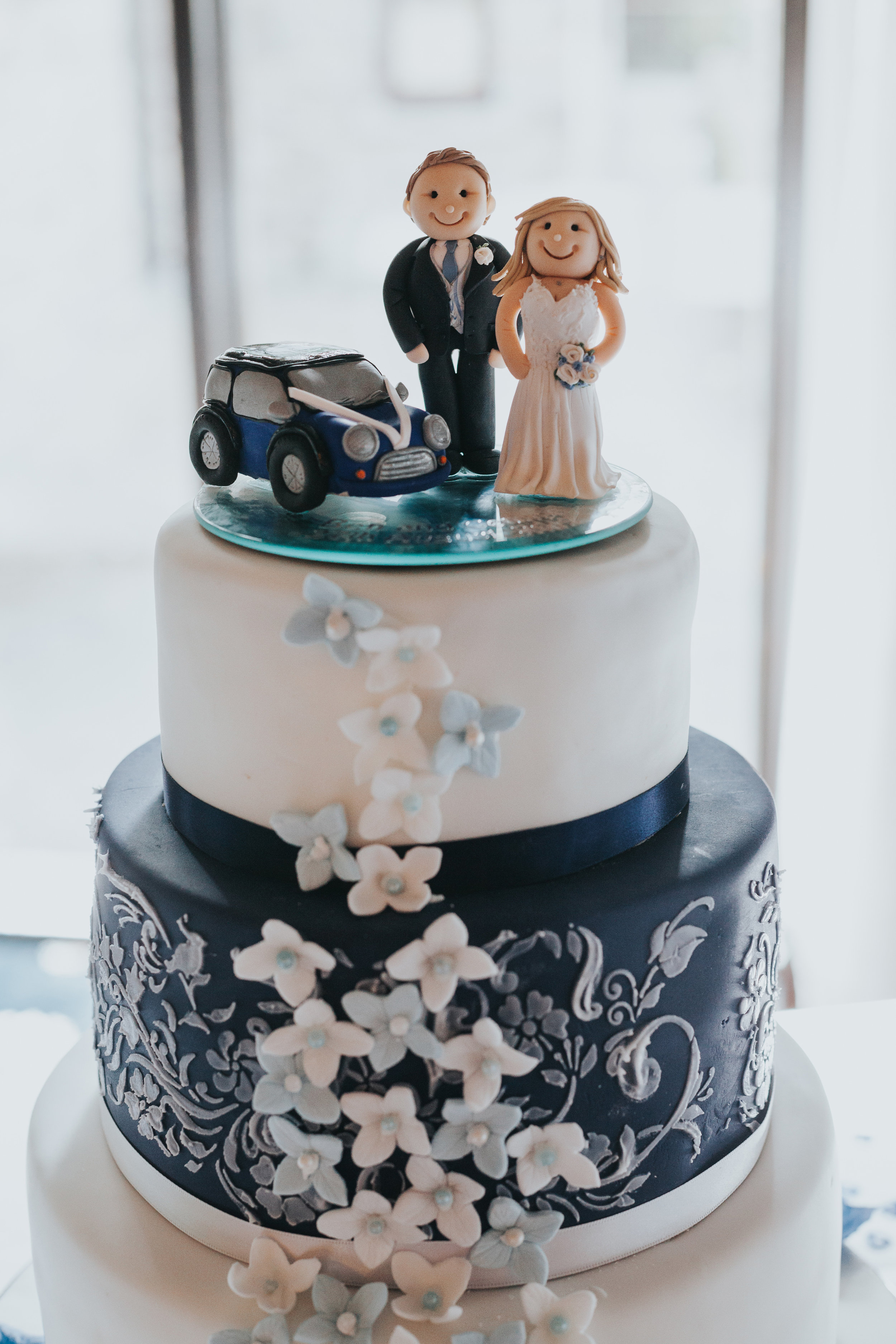 Wedding cake topped with bride, groom and blue mini. 
