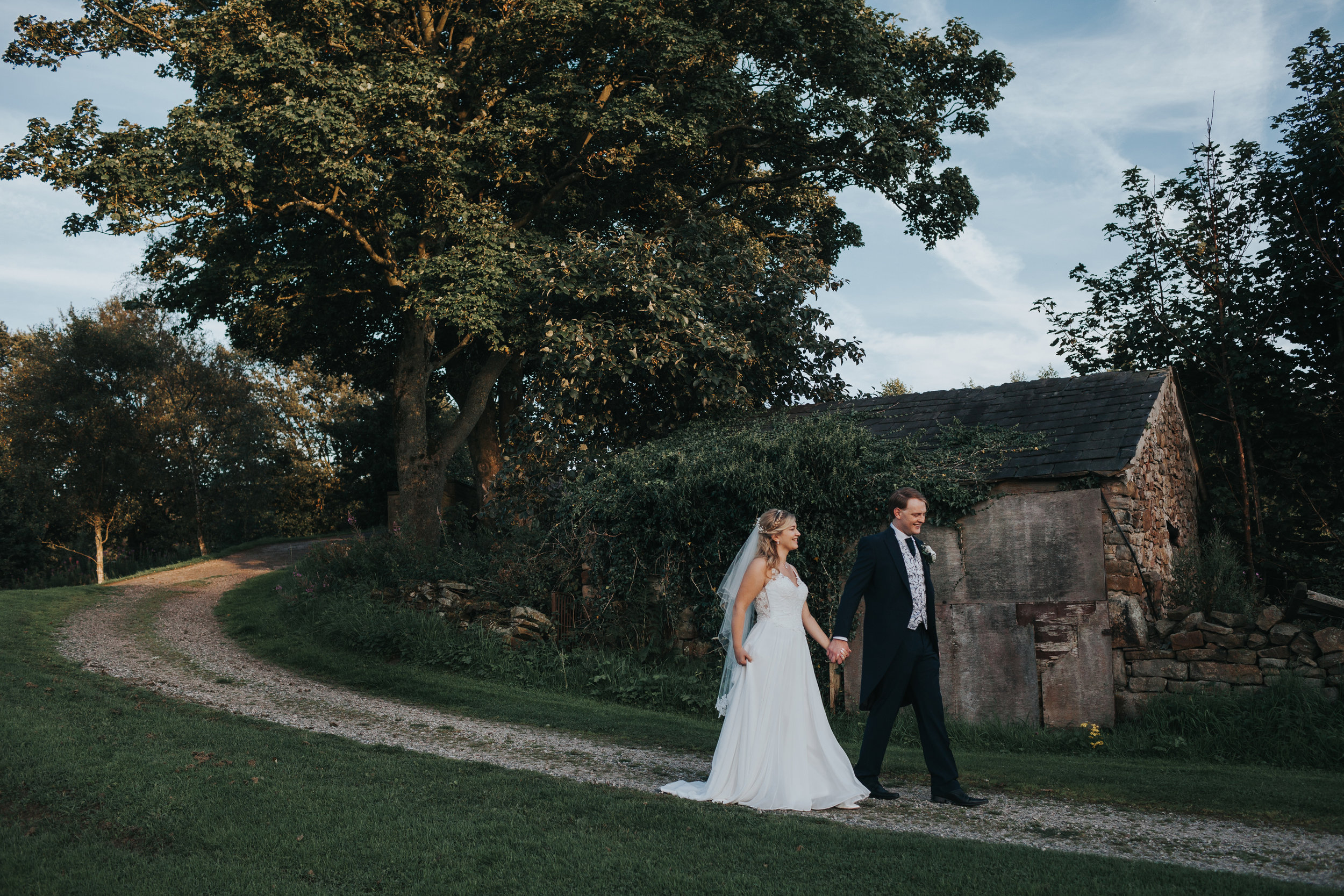 Bride and Groom walk past a derelict house. 