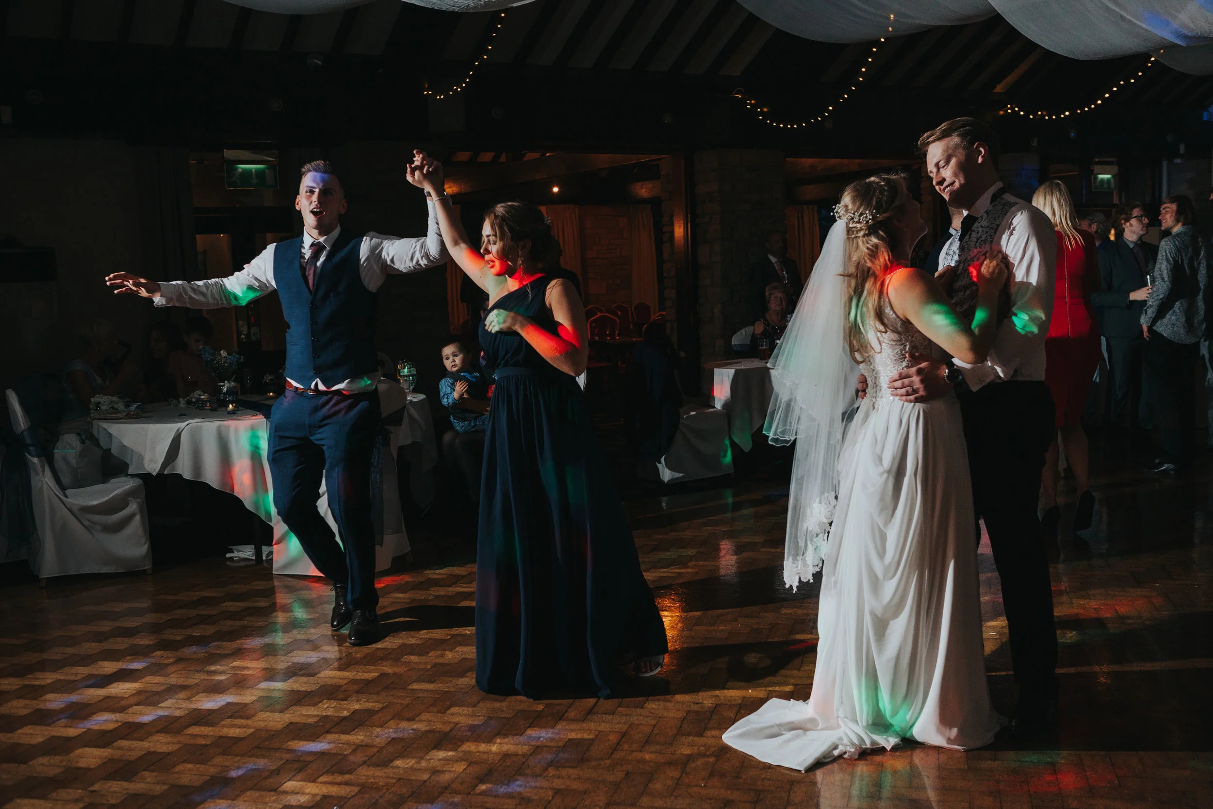 Bride and Groom dance next to the brides sister and her partner, both laughing. 