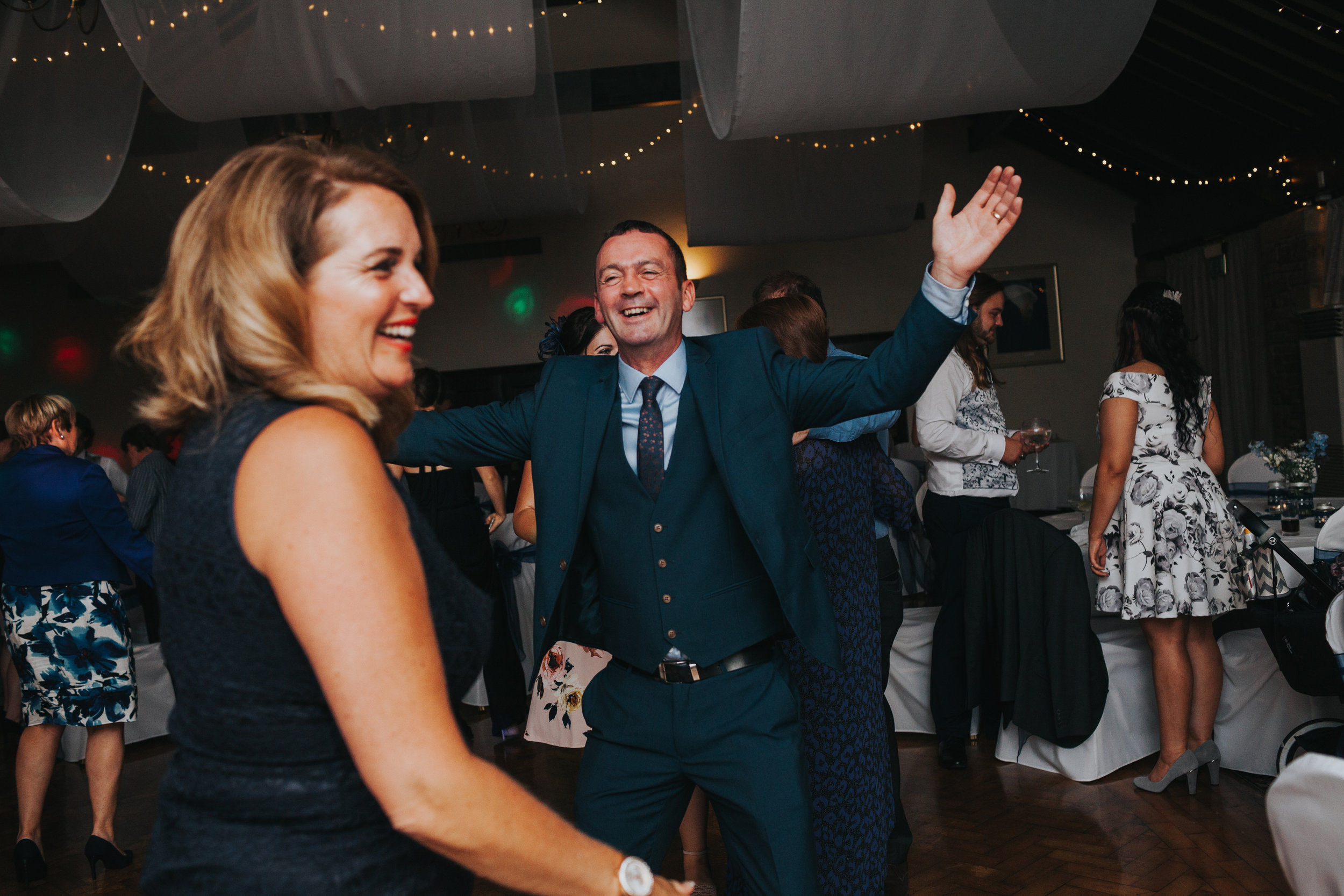 Wedding guests laughing and dancing together.