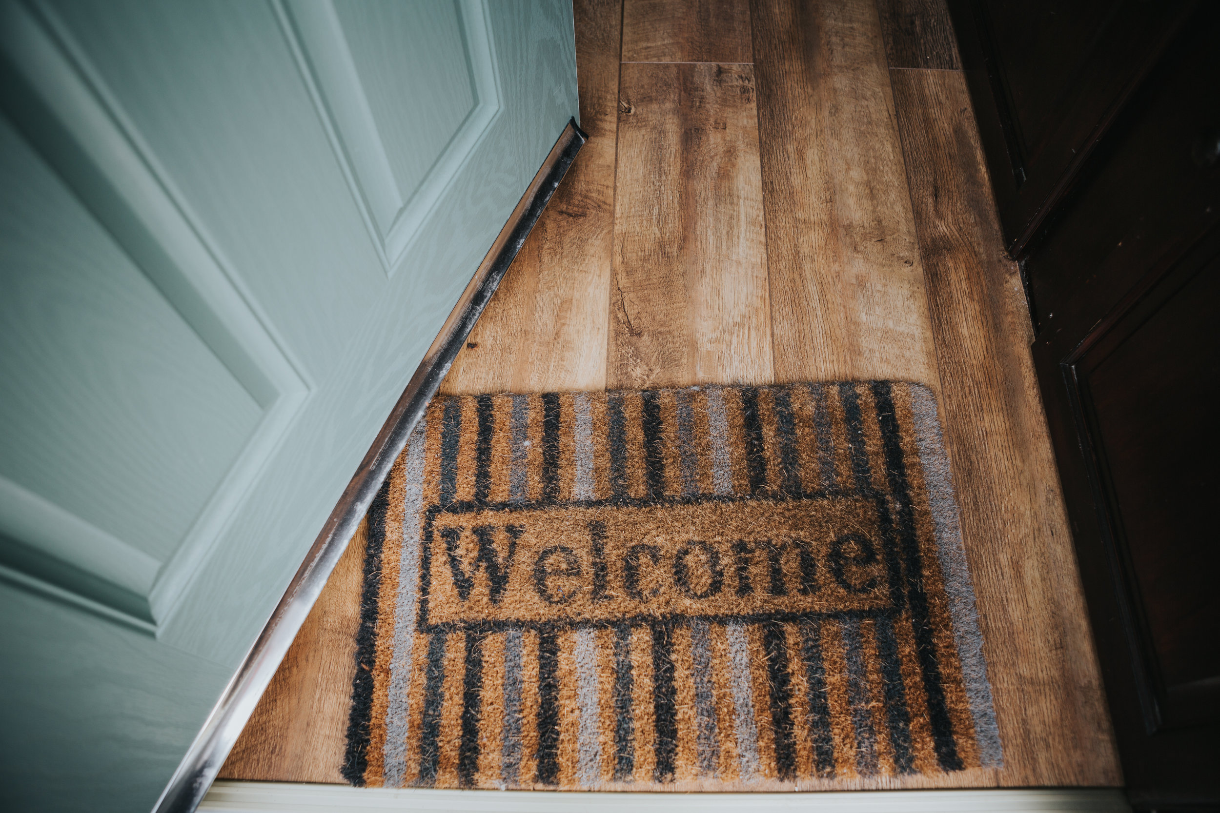 A egg shell blue door opens onto a mat that says "Welcome" at a families house in Liverpool.