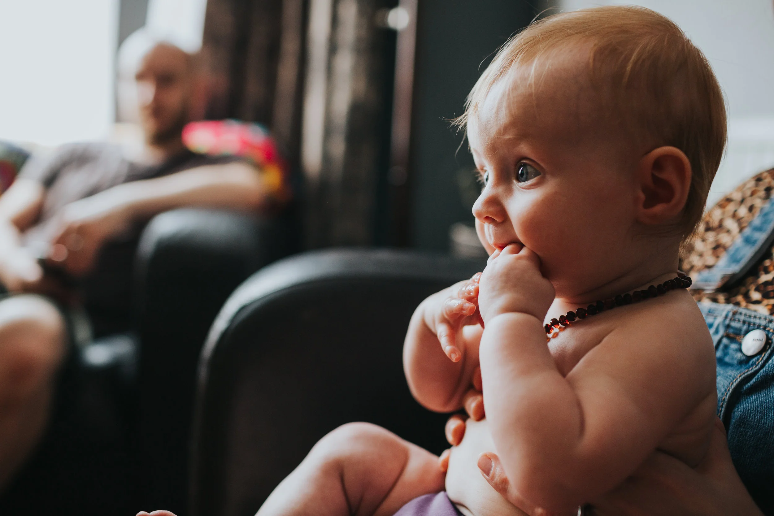 Baby watching Formula One and eating her own hand in colour. 