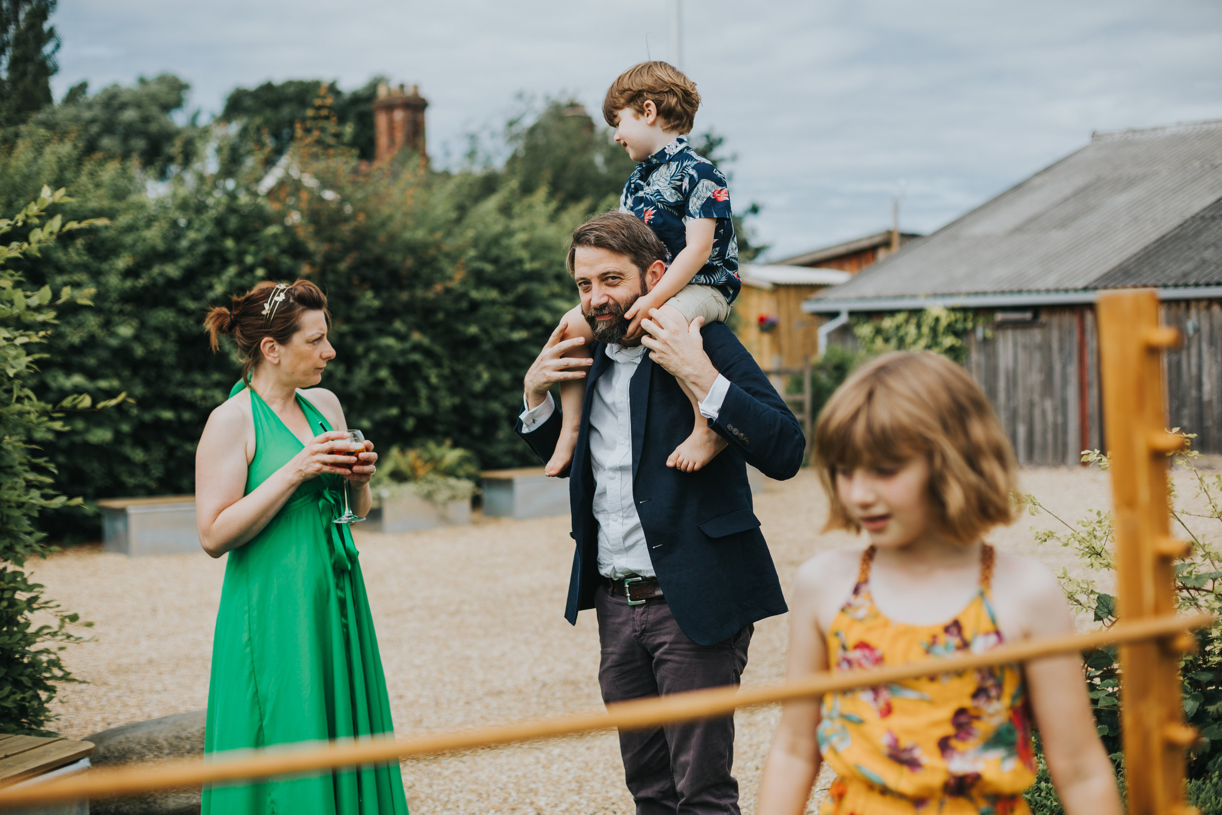 Father has his son sit on his shoulders as his daughter and wife play limbo.