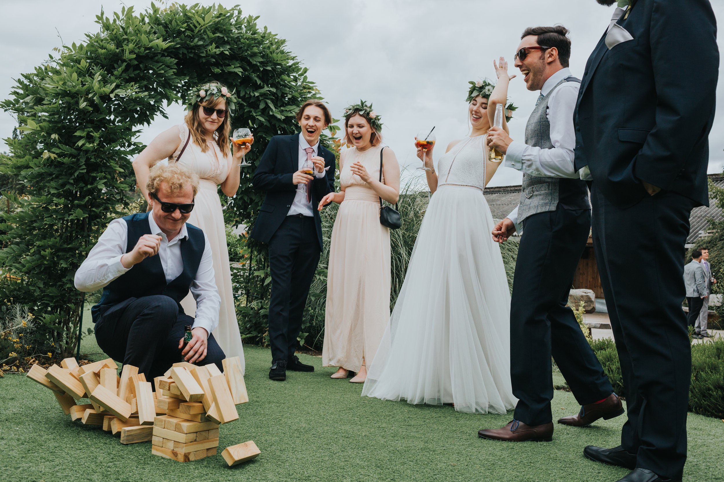 Bridal party roar with laughter as wedding guests topples the Jenga tower. 