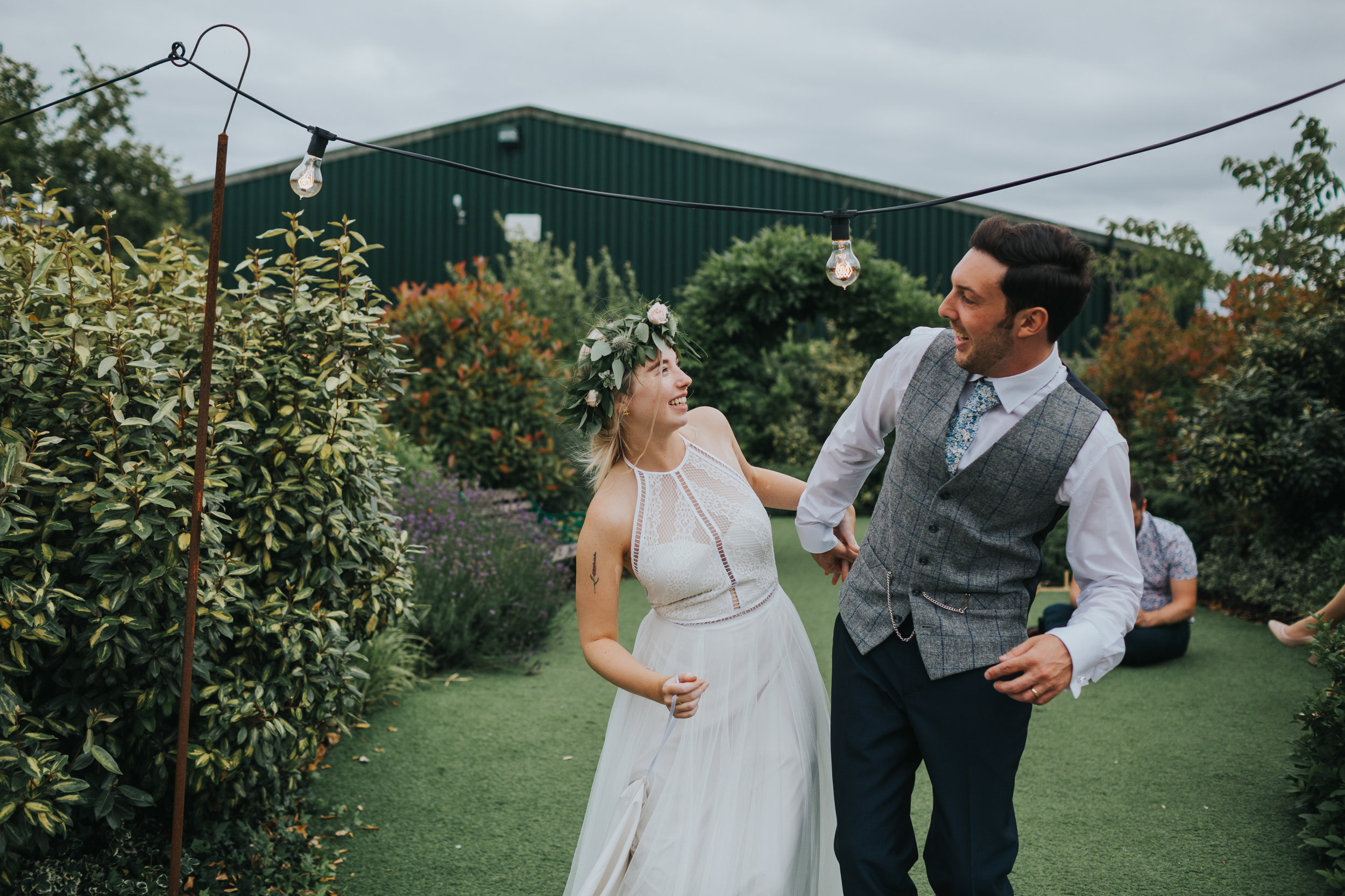 Bride and groom bend together to avoid getting hit on the head with a festoon light at Owen House Wedding Barn. t 