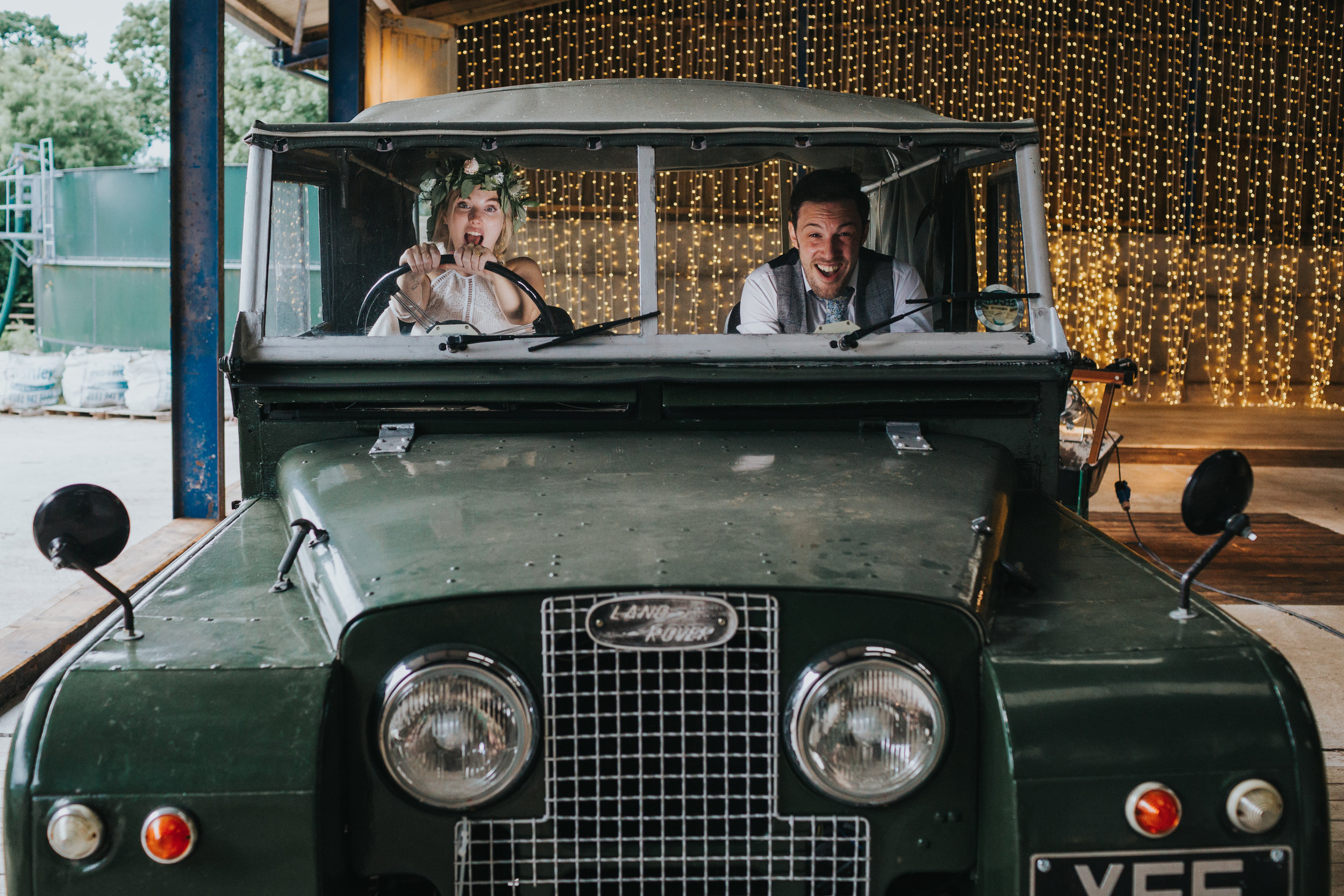 The bride and groom take the land rover for a spin. The bride is driving, but doesn't have a license. Everyone looks scared. 