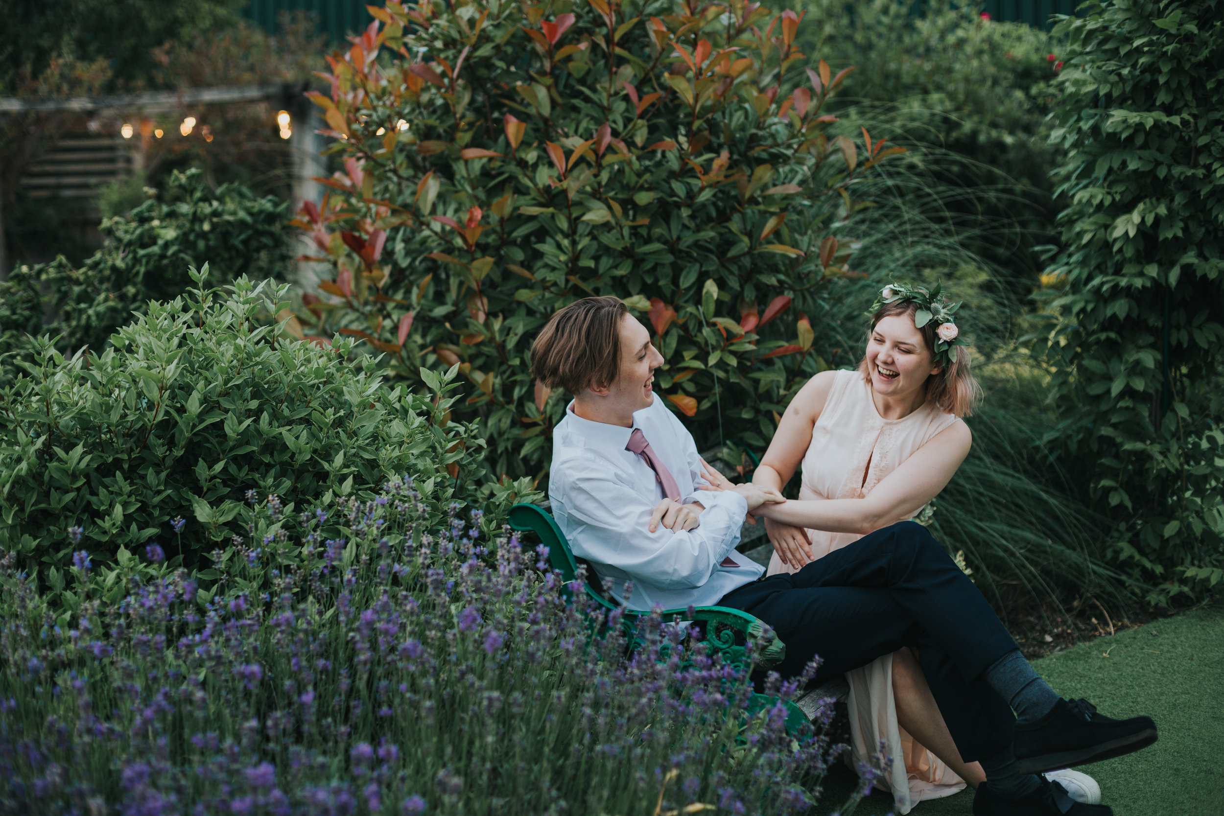 Bridesmaid and wedding guest laugh together.