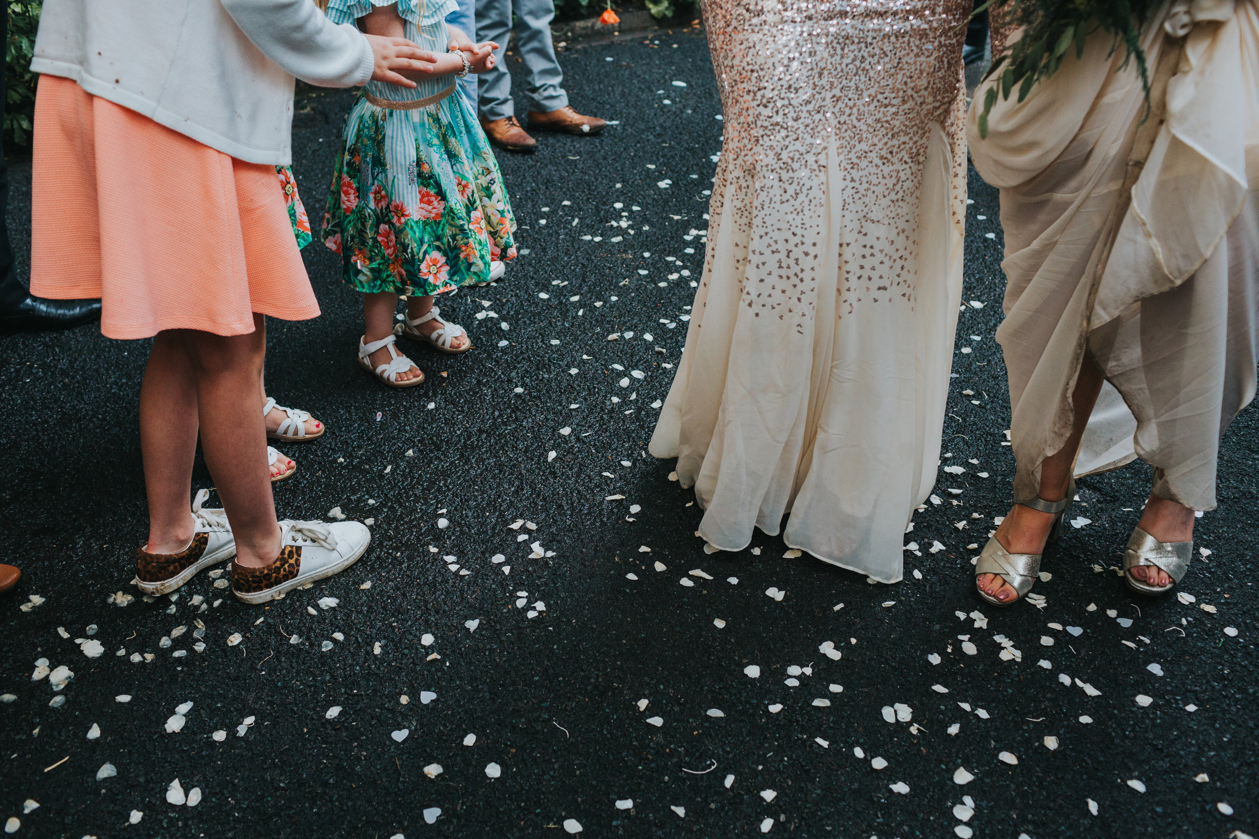 Confetti covers the floor next to wedding guests pretty shoes and dresses. 