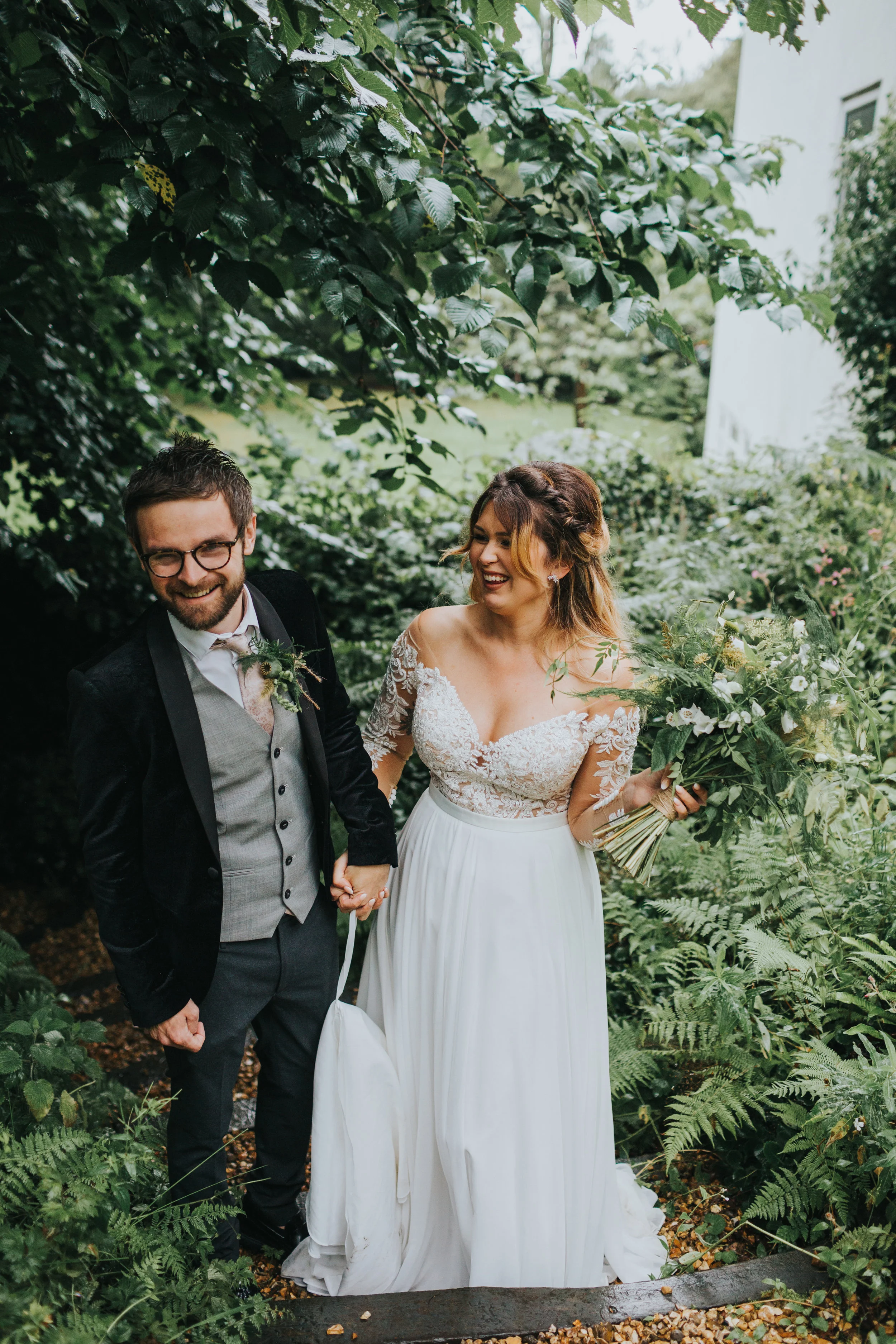 Bride and groom laugh together under the trees. 