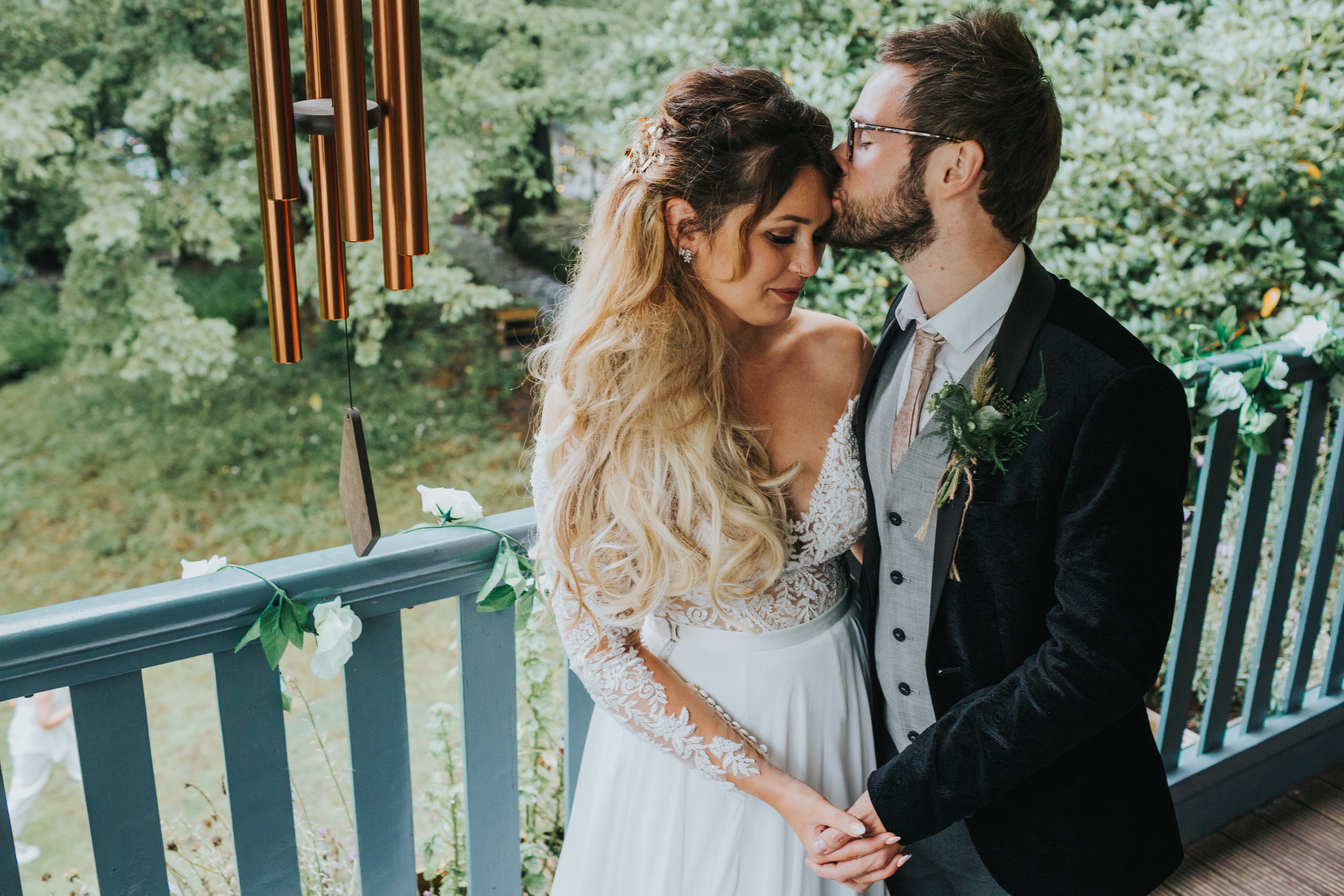 Groom kisses his bride on his head. 