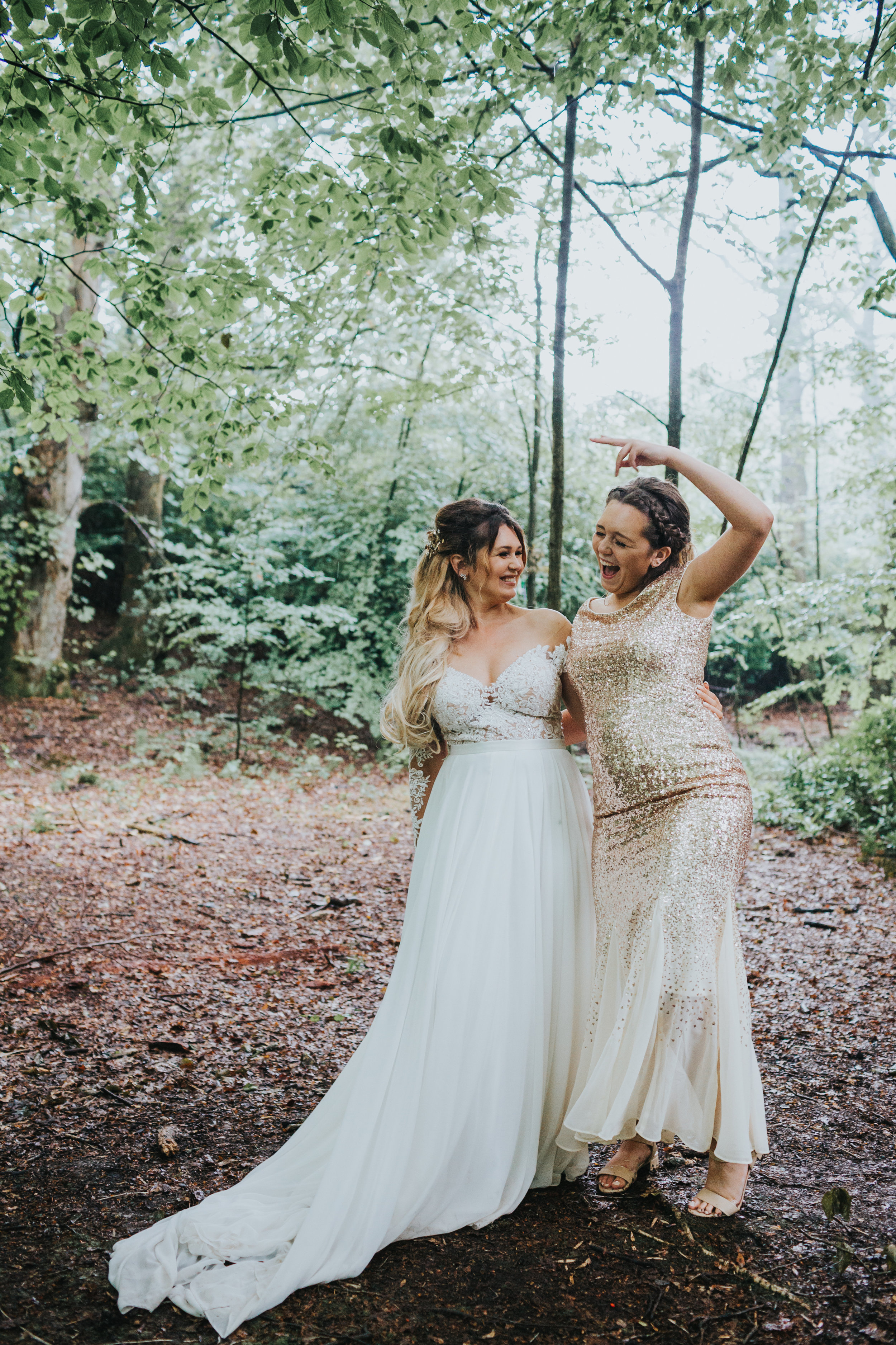 Bride and her sister stand together laughing. 