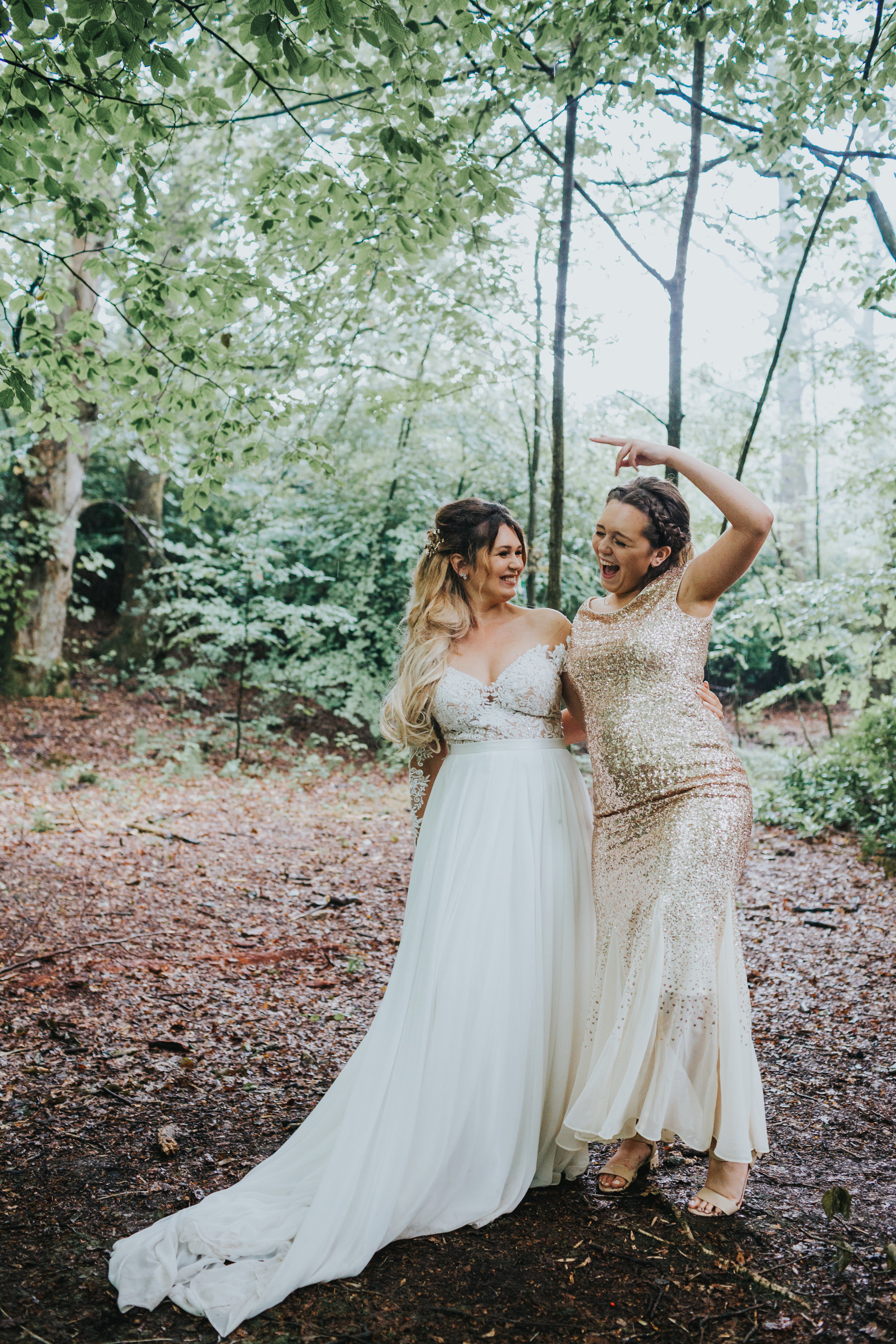 Bride and her sister stand together laughing. 