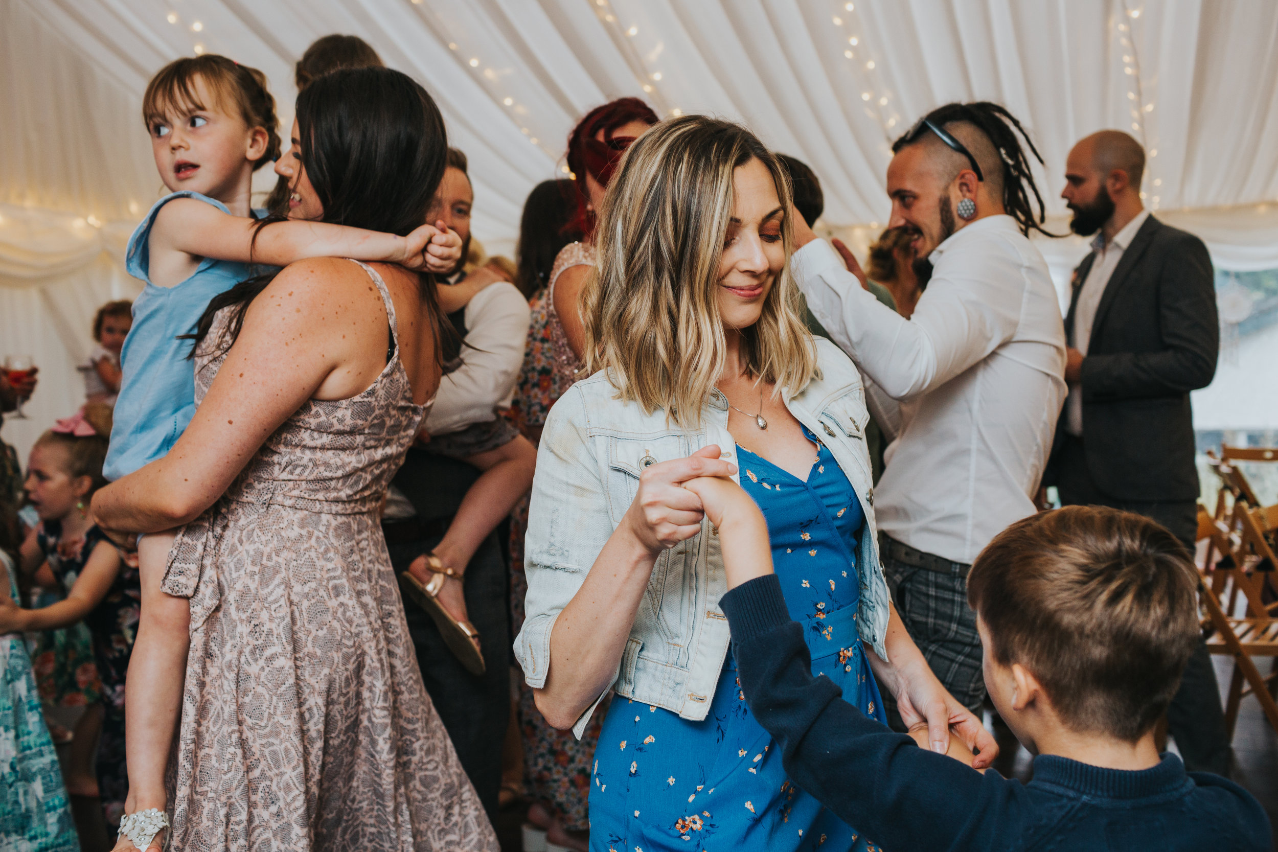 Two women dance with their children. 