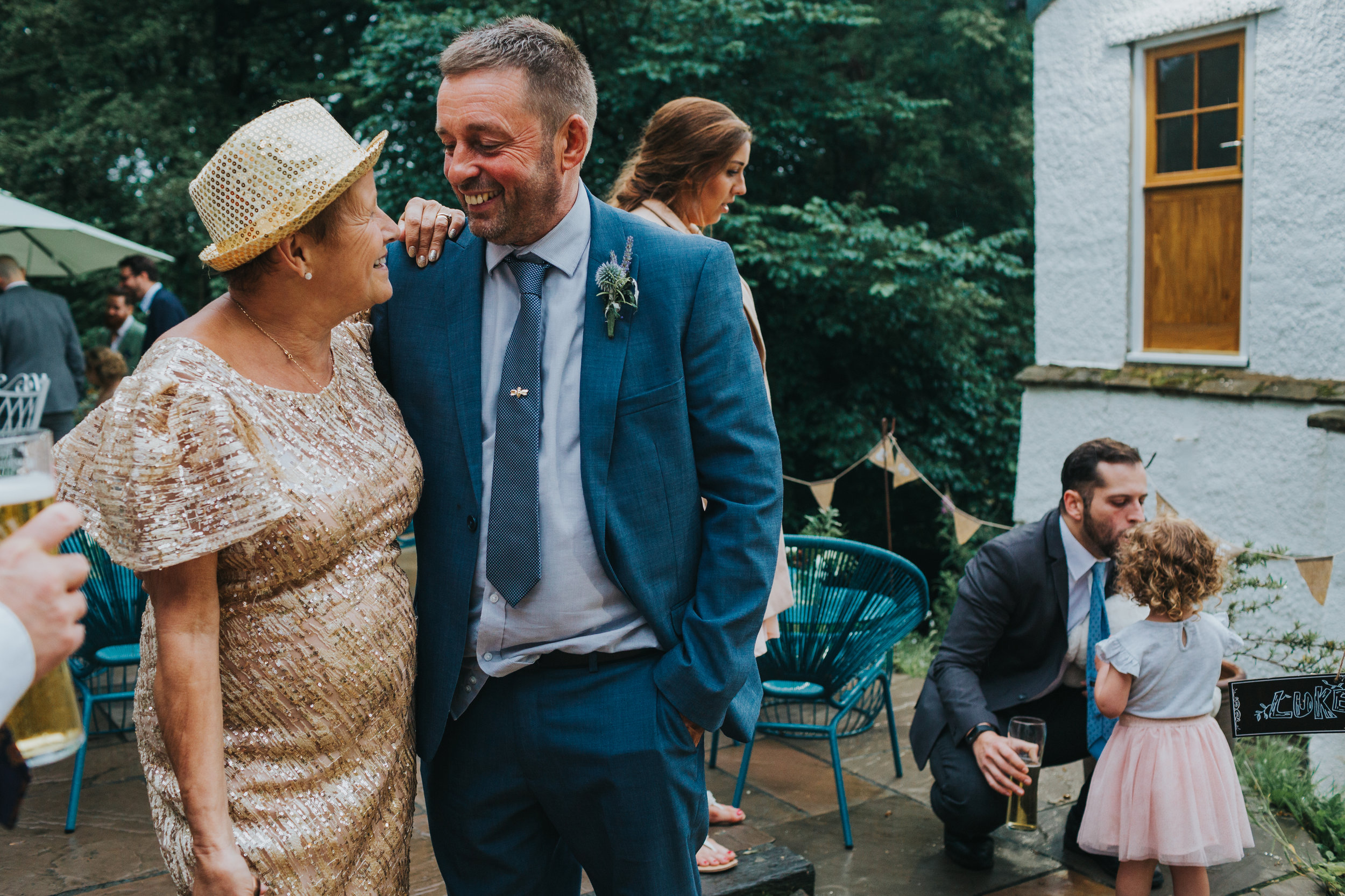 Guests laugh together and a child has a kiss from her dad in the back ground. 