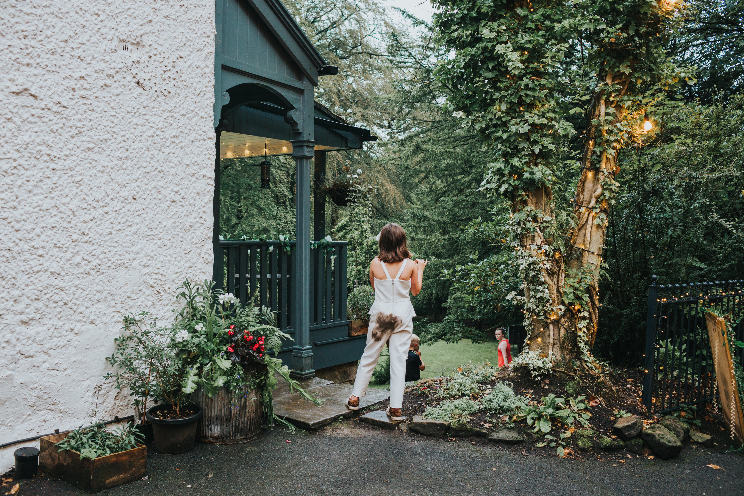 Little girl dressed all in white stands with a muddy bum.
