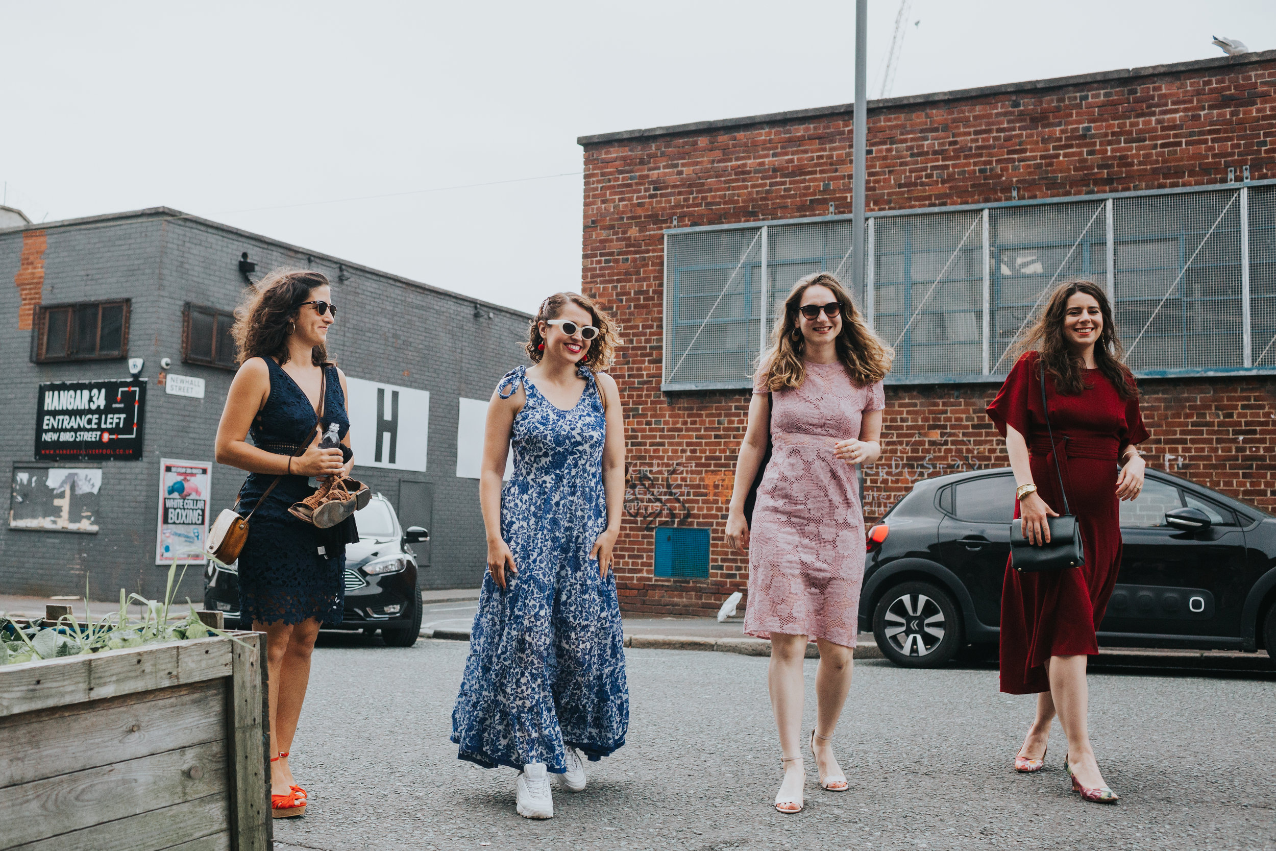 4 female wedding guests arrive together smiling. 