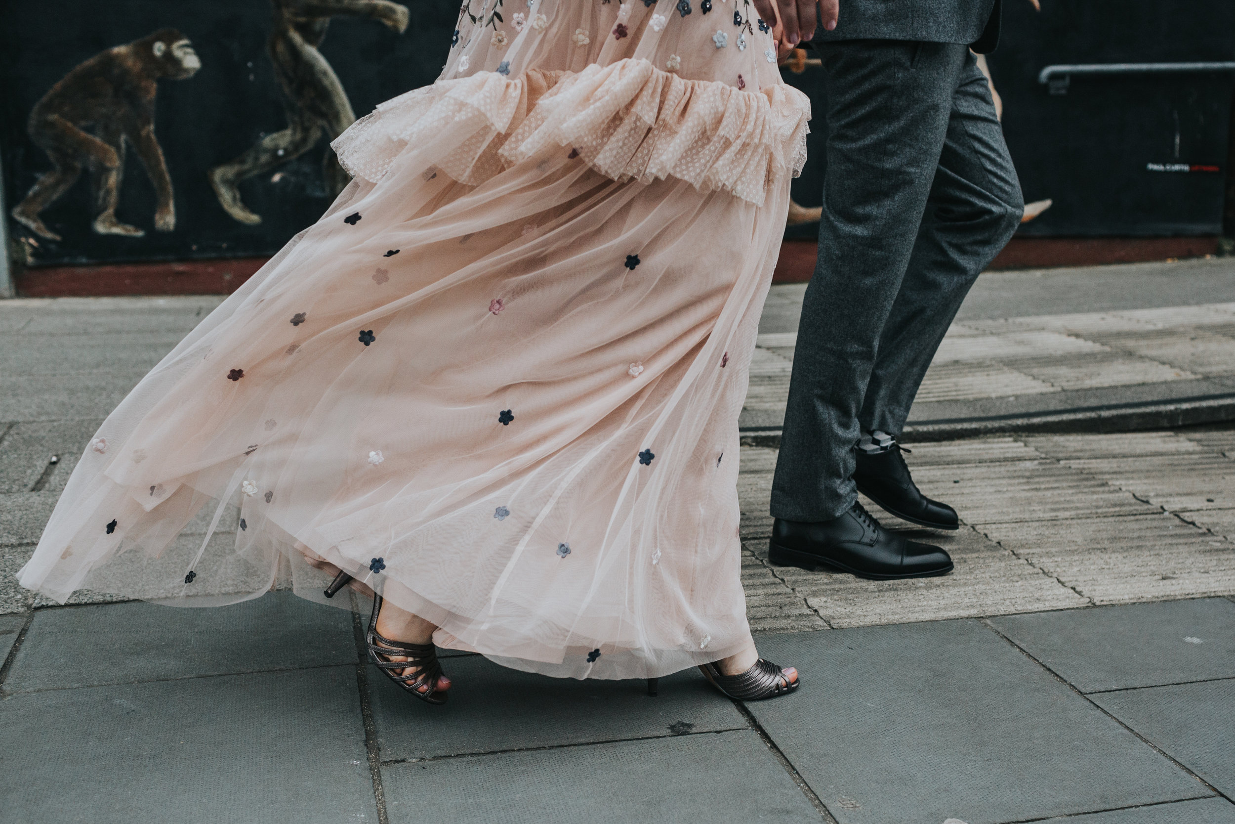 Bride and Groom walk together as the brides dress blows on the wind showing off her heels. Monkeys in the background.
