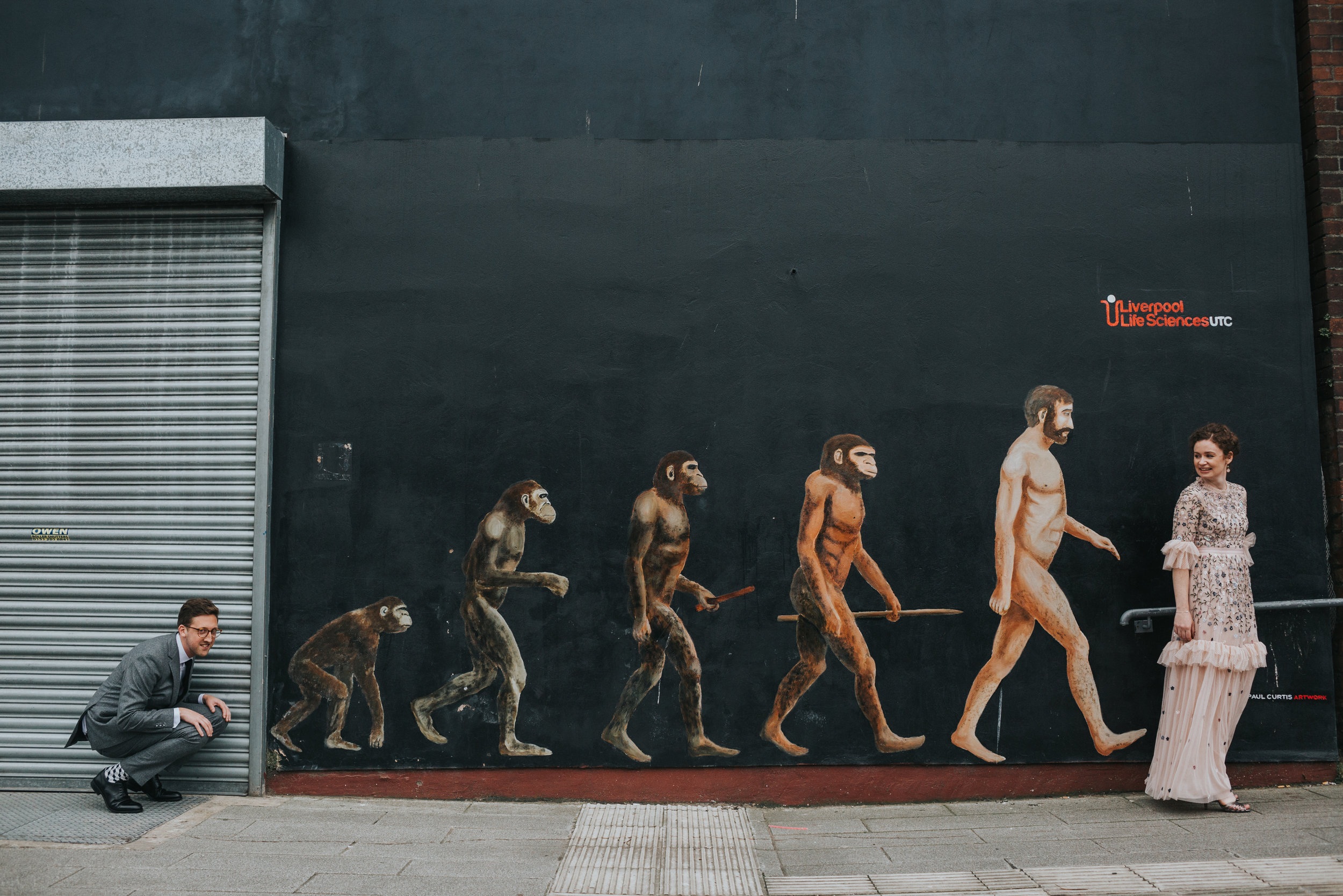 Bride and Groom joke around with the evolution of Man mural.